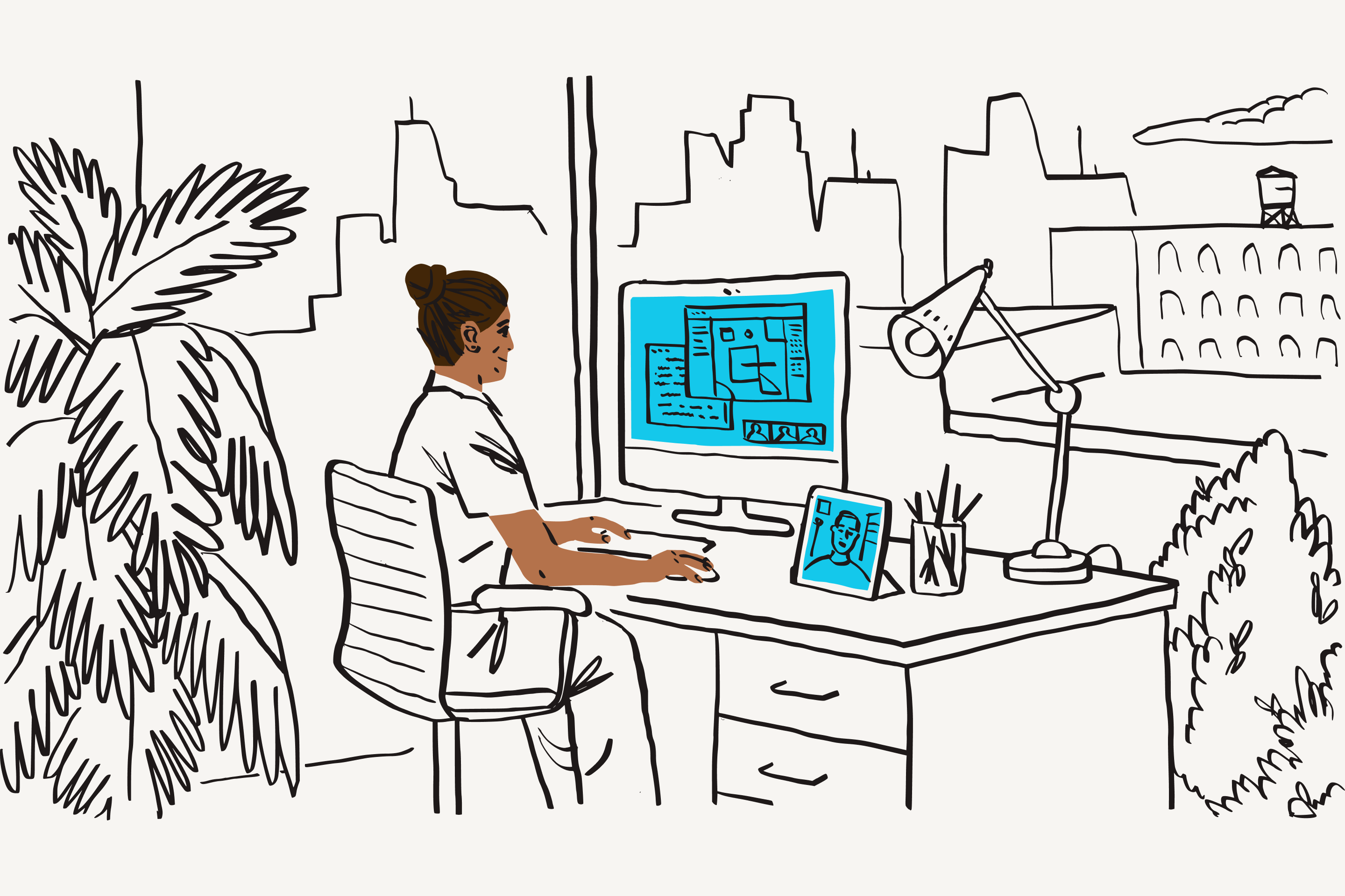A professional sitting at a desk working on a monitor with a blue screen and a tablet with a blue screen beside them.