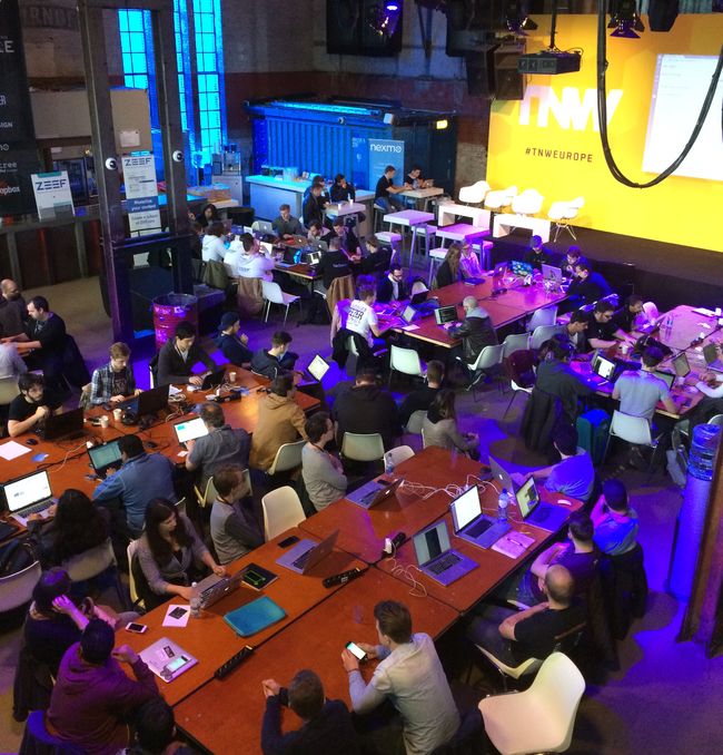 An open plan room with lots of people at desks with computers
