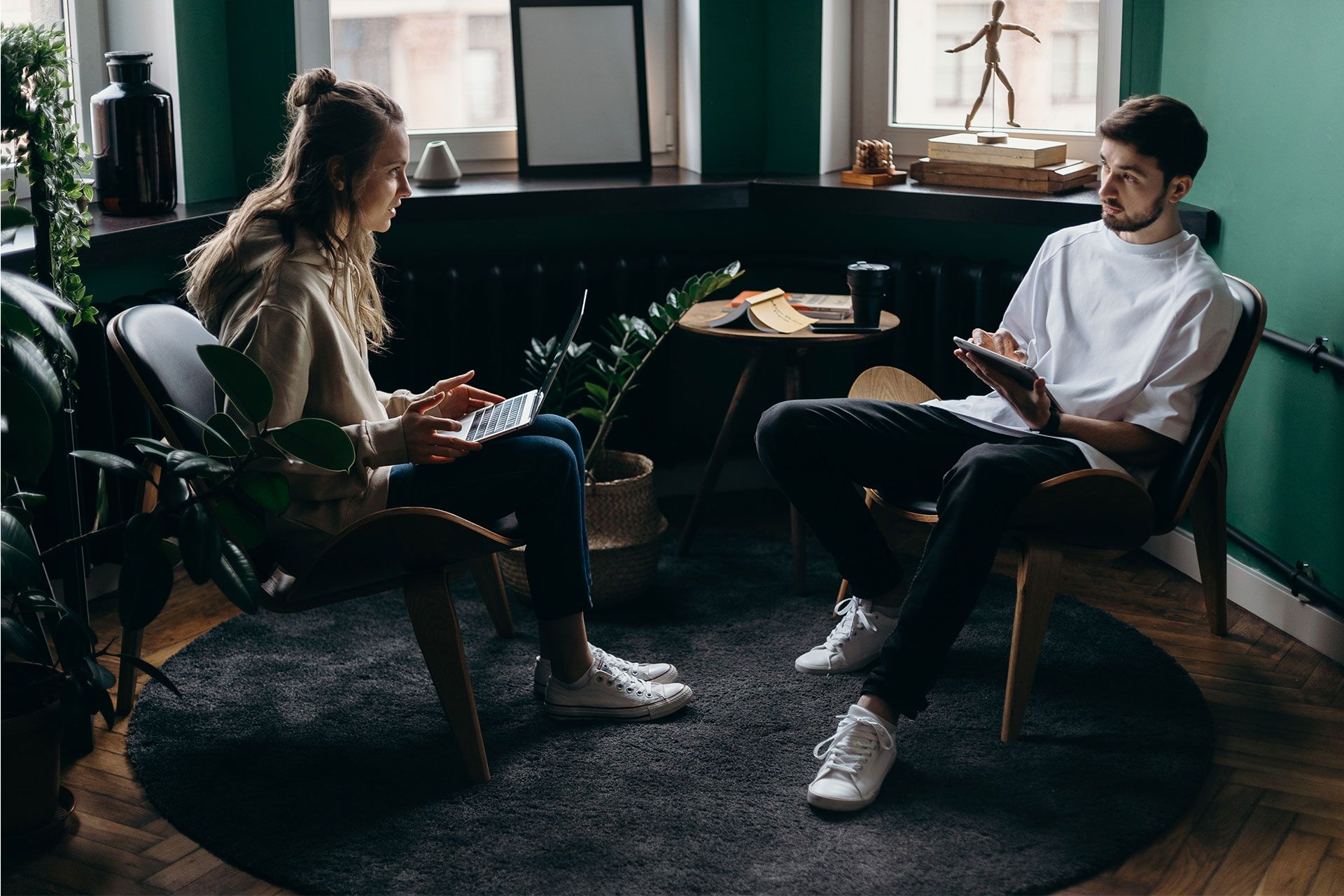 Two people discuss workflow management, using a laptop and tablet to organize tasks and collaborate efficiently.