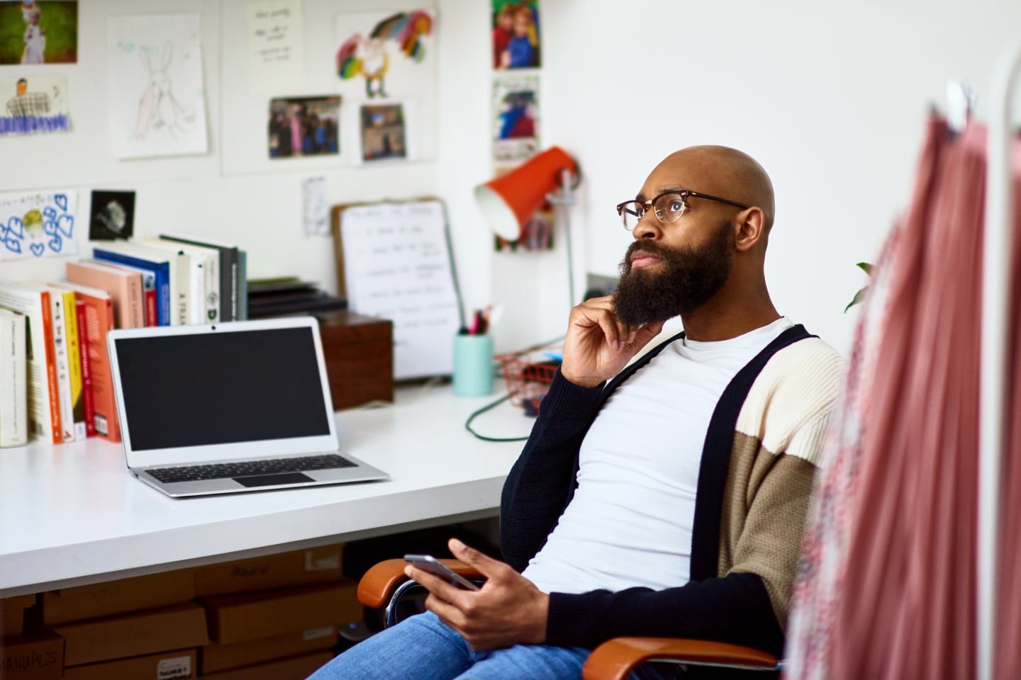 Person sits in a home office, holding a mobile device and thinking about how to recover their lost offline files.