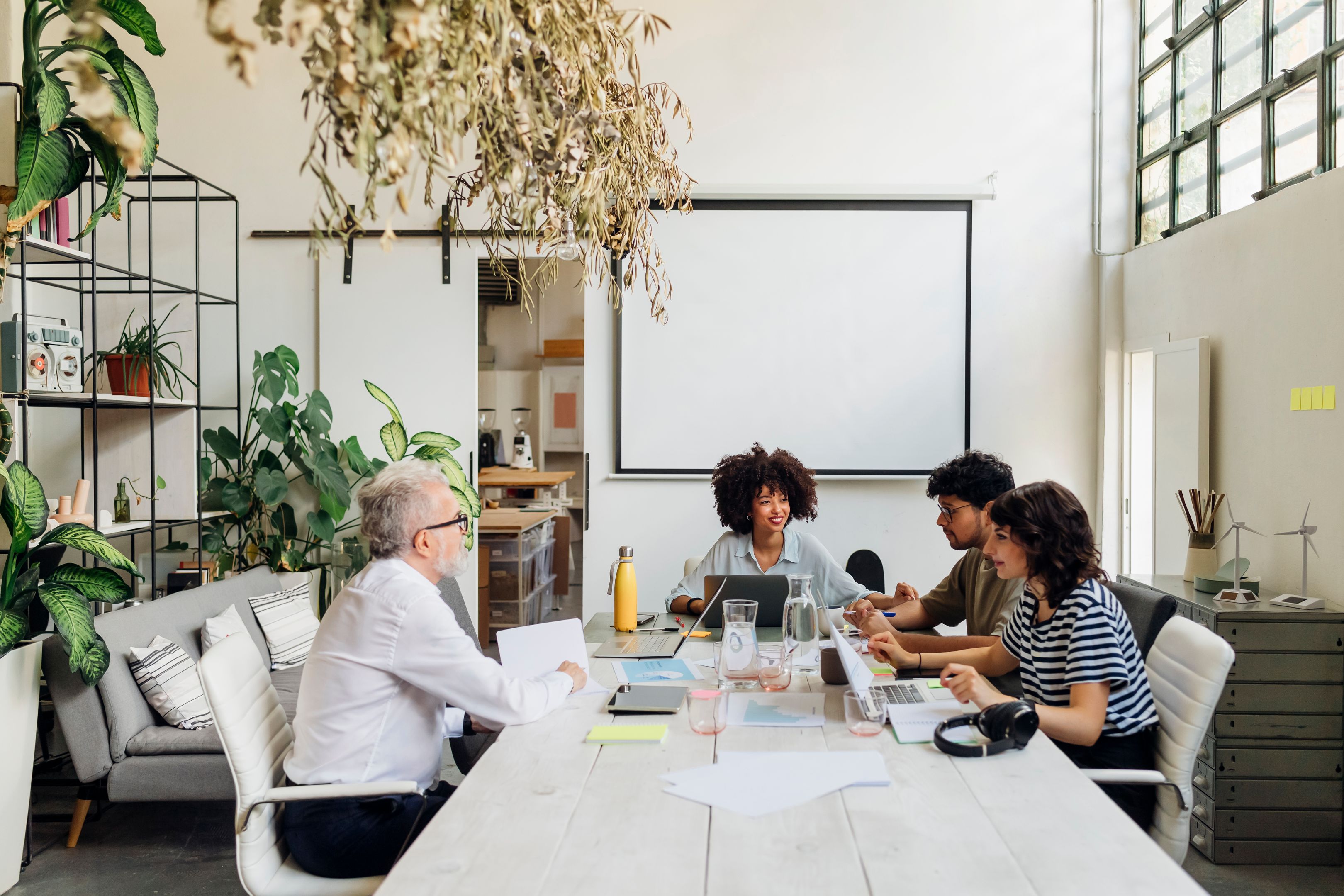 Four people engaged in a meeting at a table in a modern office space.