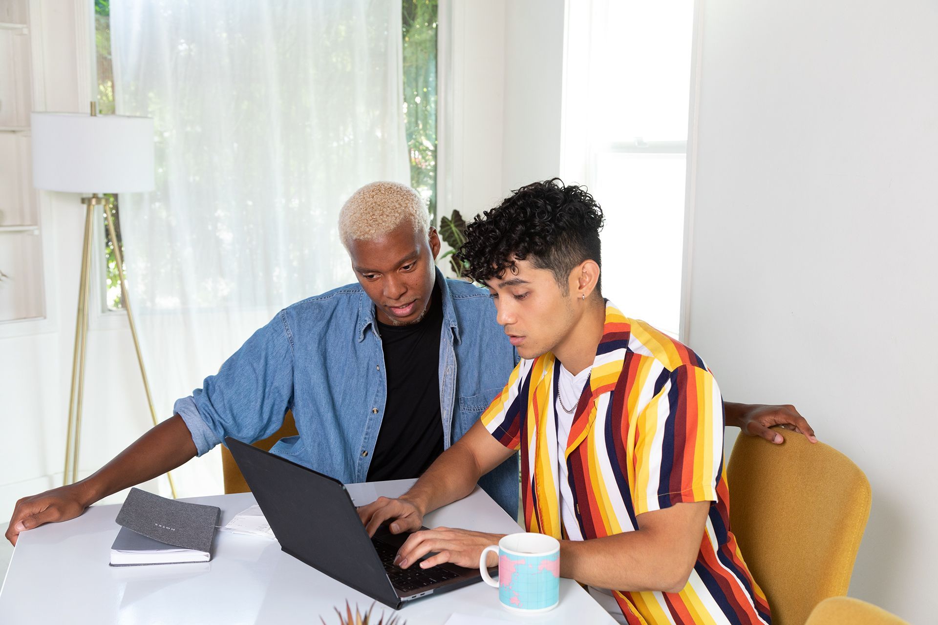 Two people work together on a laptop at a table, demonstrating how to quickly and easily reorder pages in a PDF.