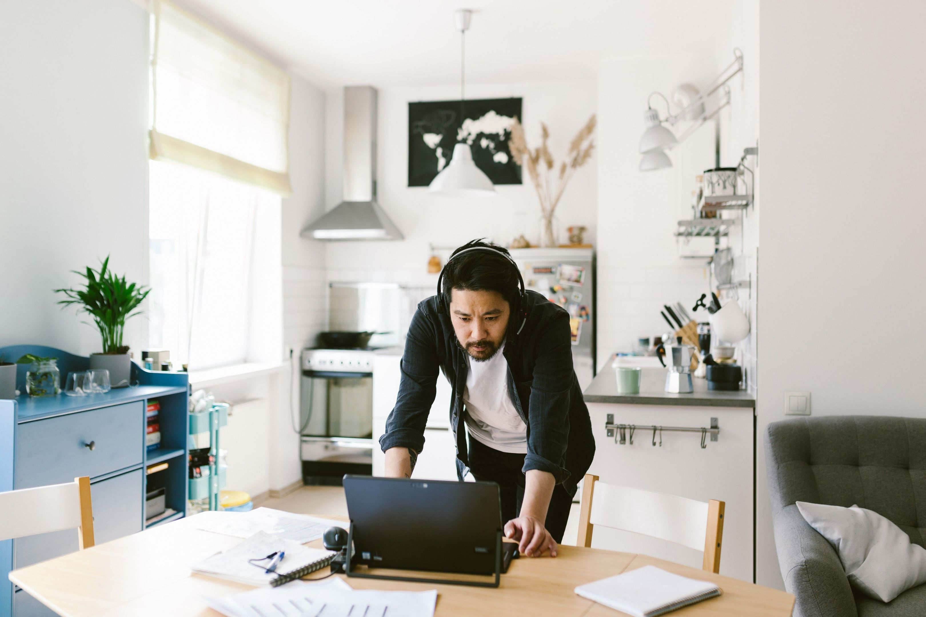 Une personne travaillant à distance qui utilise un ordinateur portable et un casque pour participer à une réunion hybride depuis son environnement de travail personnel