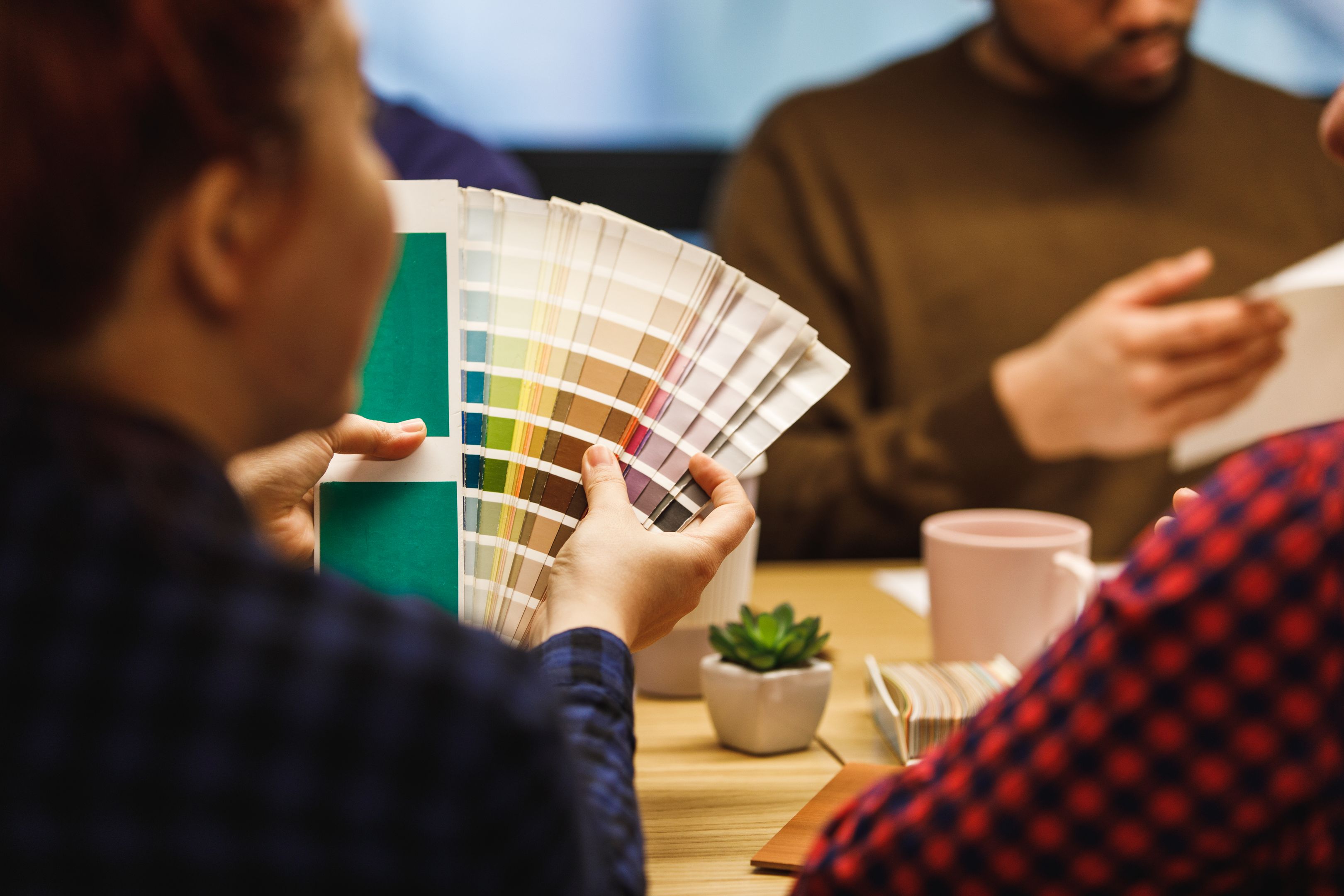 Person holding a color palette swatch during a discussion in a meeting.