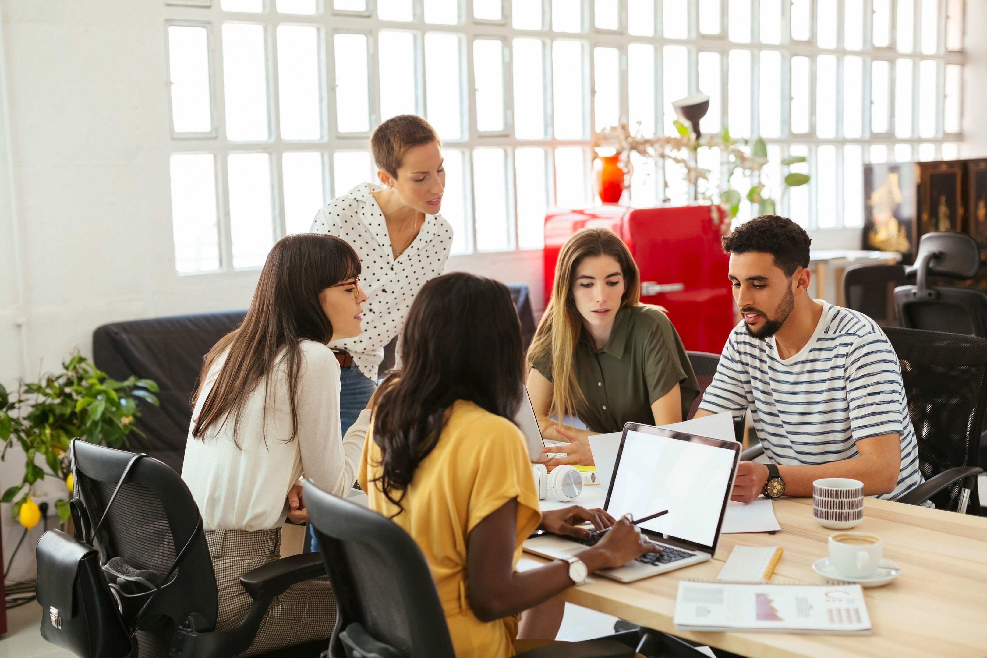 A team gathers around a table discussing ideas, reflecting how AI may support or challenge collaboration and creativity.