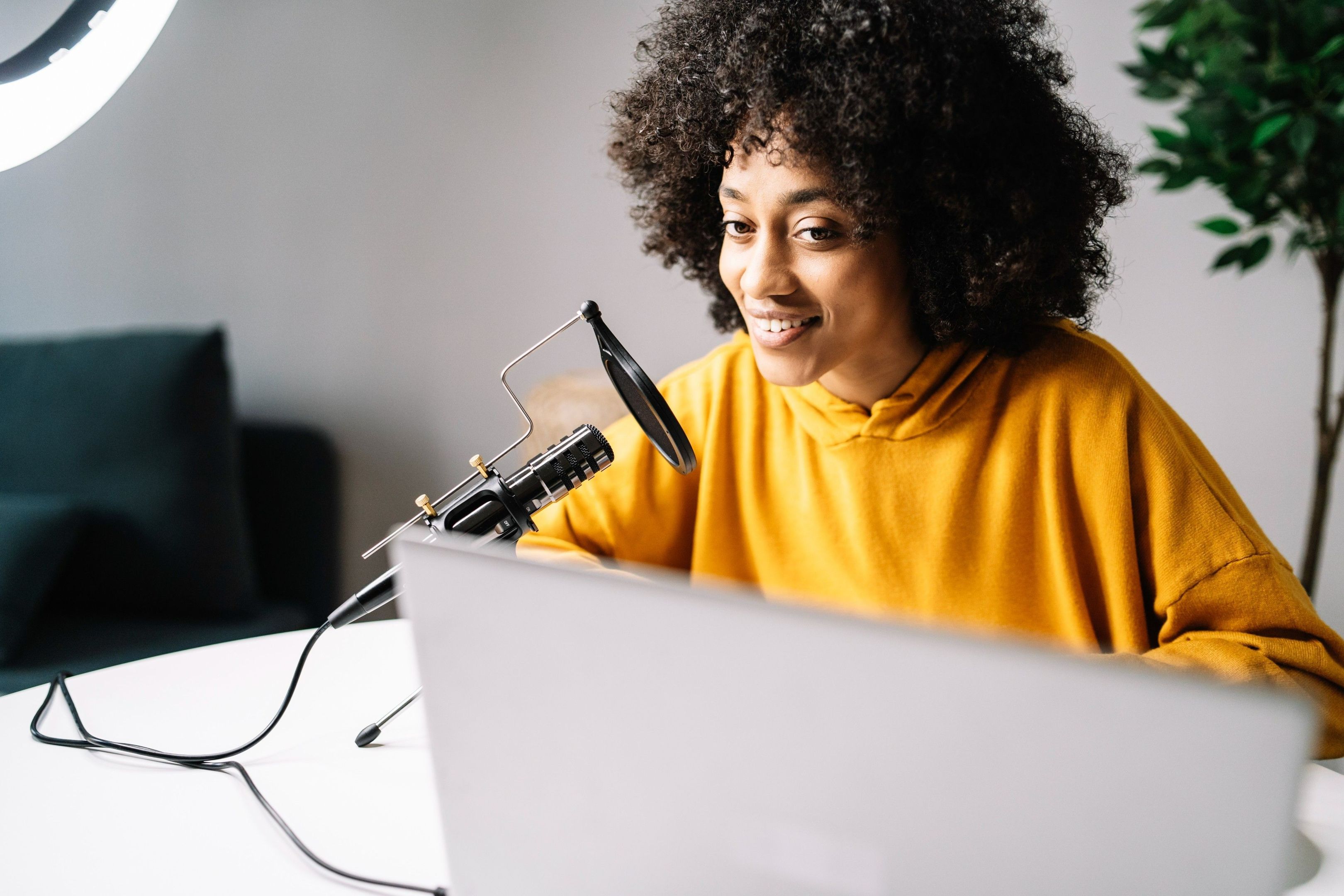 A person records a video presentation using a laptop and external microphone.