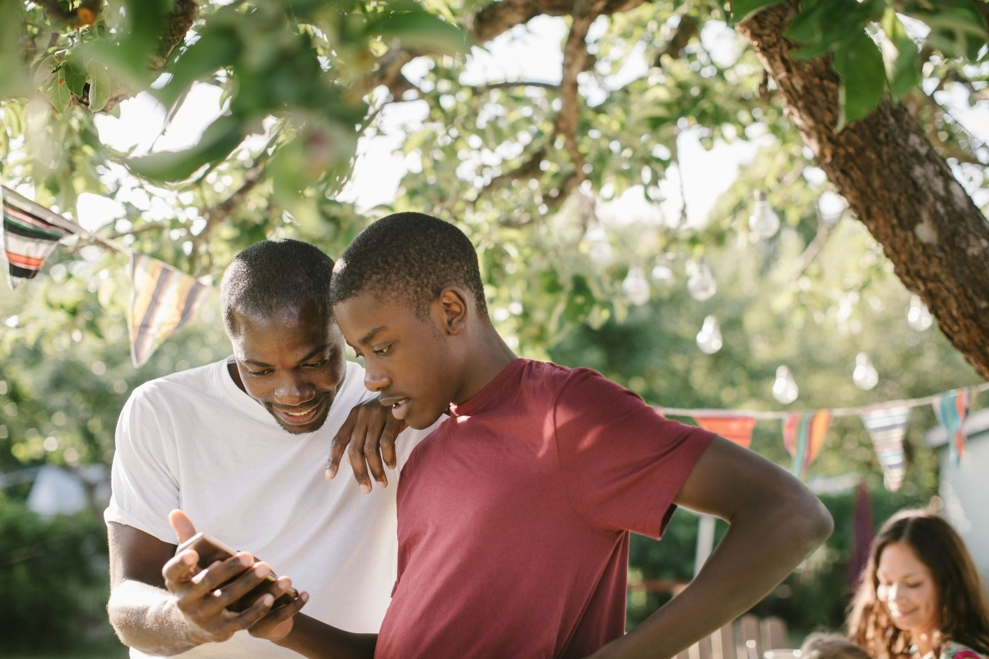 Two people watch a video on a mobile device at a family gathering.