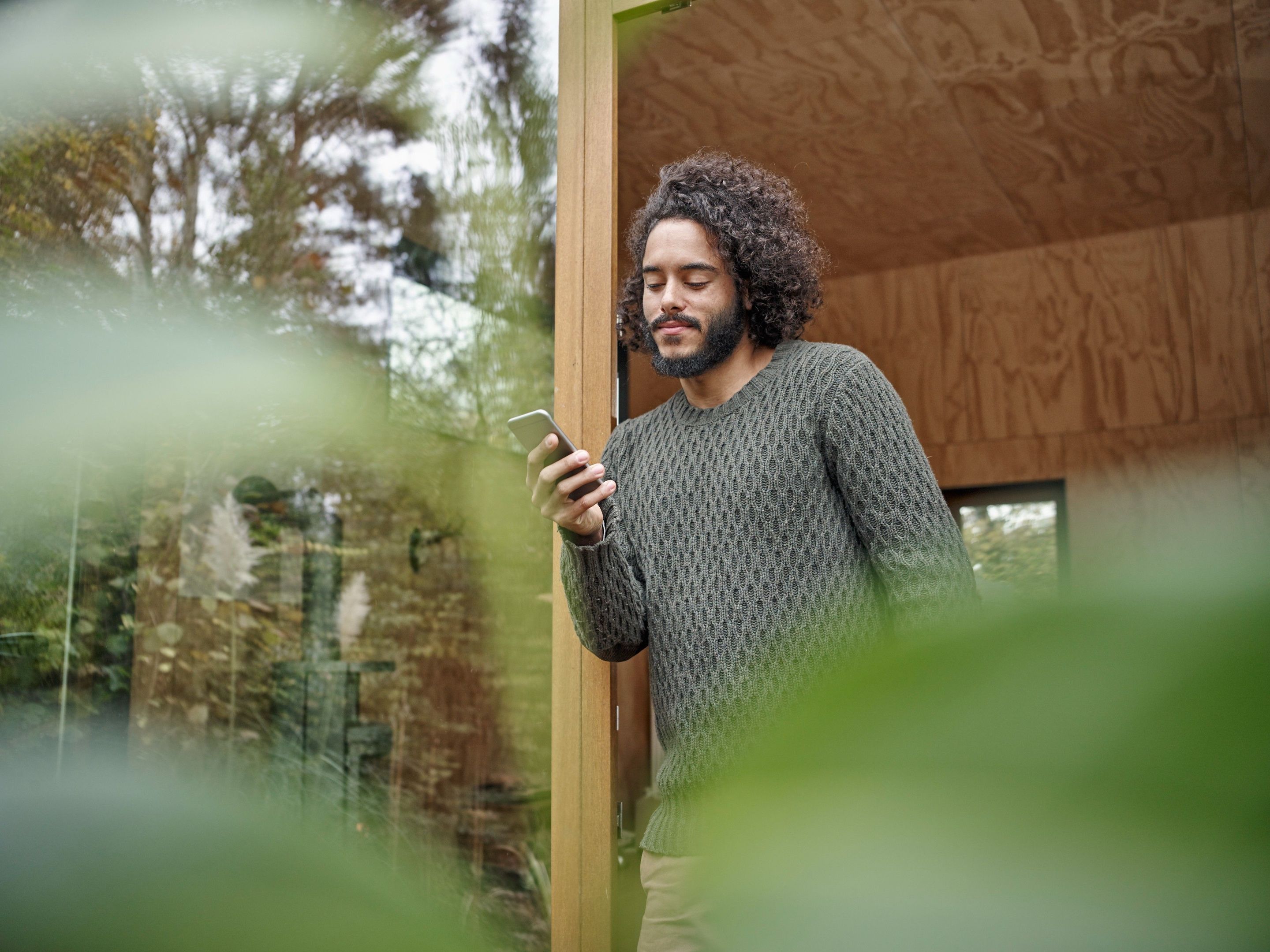 A creative professional leans against a doorway, sharing a large video over WhatsApp from a shoot location.