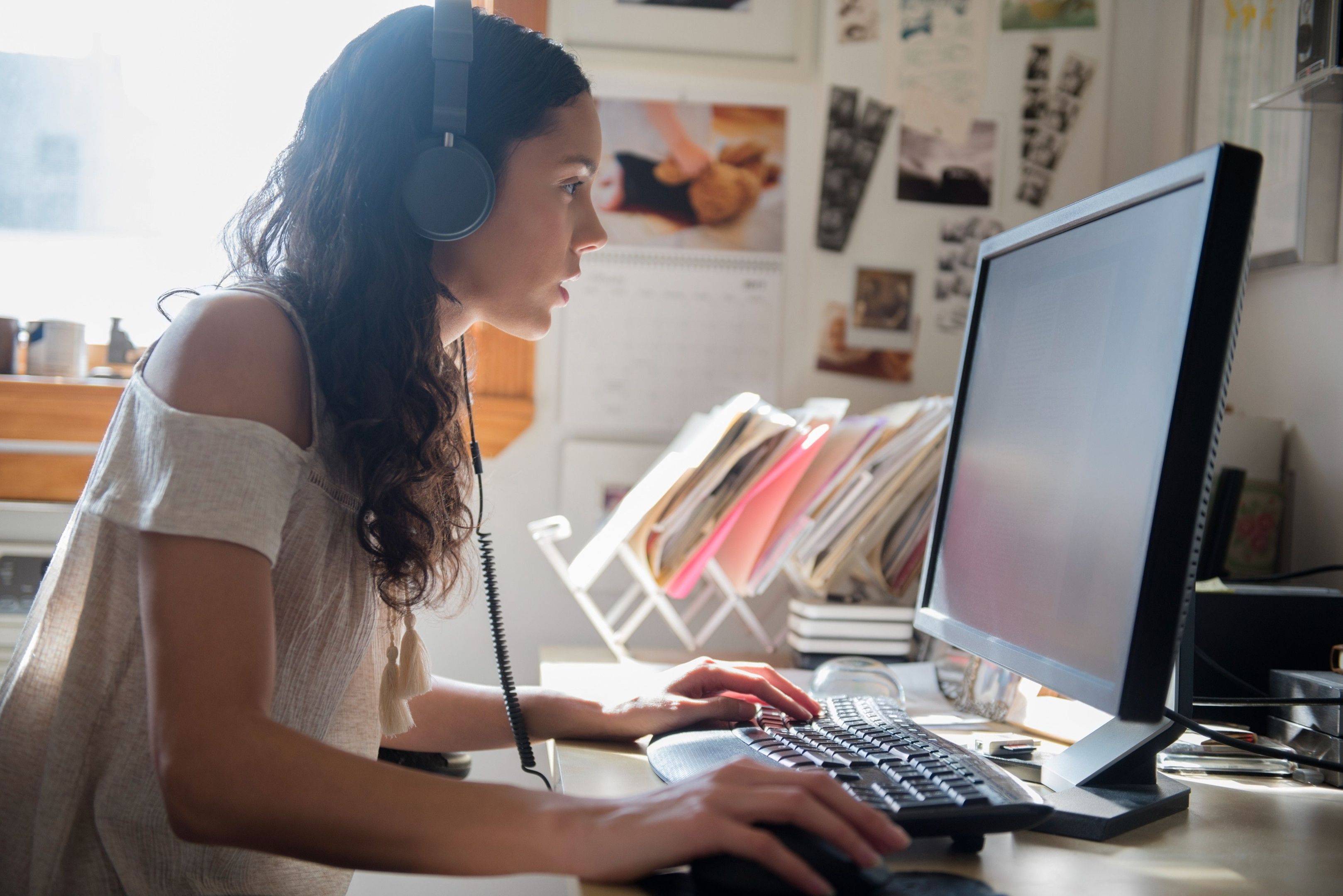 A person with headphones on at their desk works on editing a video.