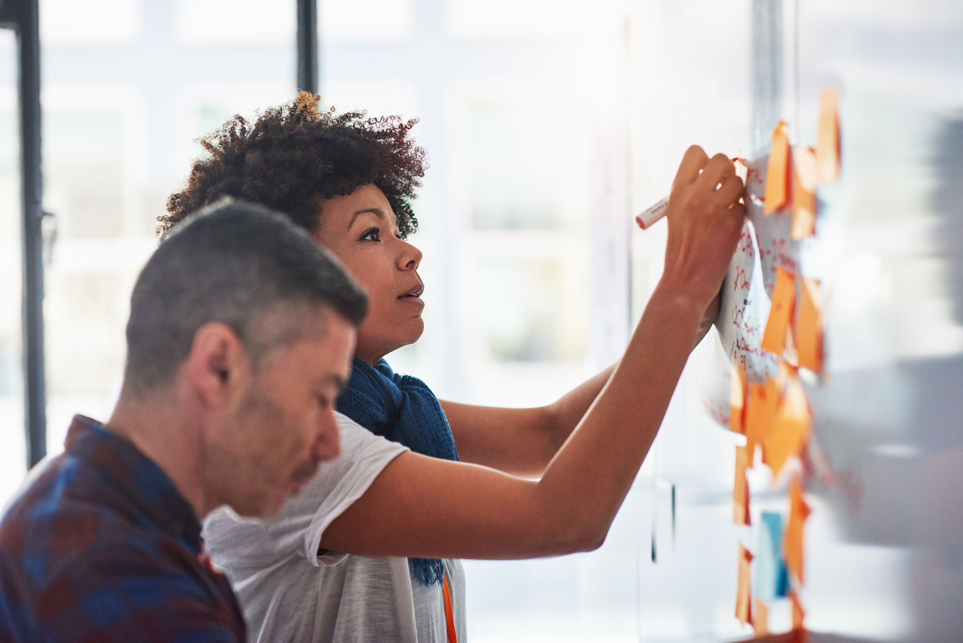 Two people planning on a whiteboard using sticky notes.