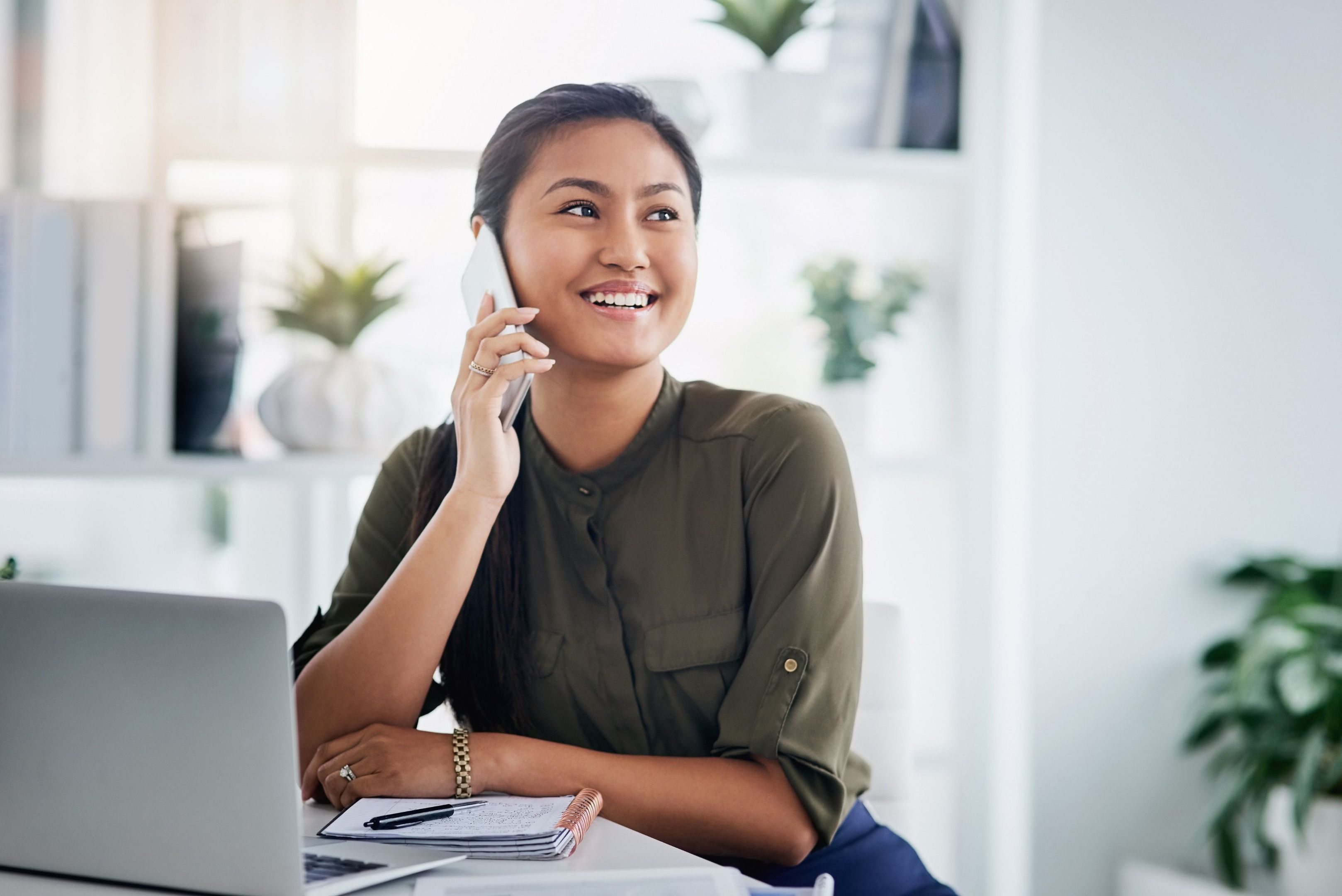 A professional smiles while speaking on their mobile device.