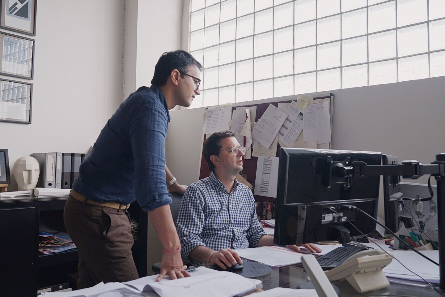 To menn ser på en datamaskinskjerm ved et skrivebord