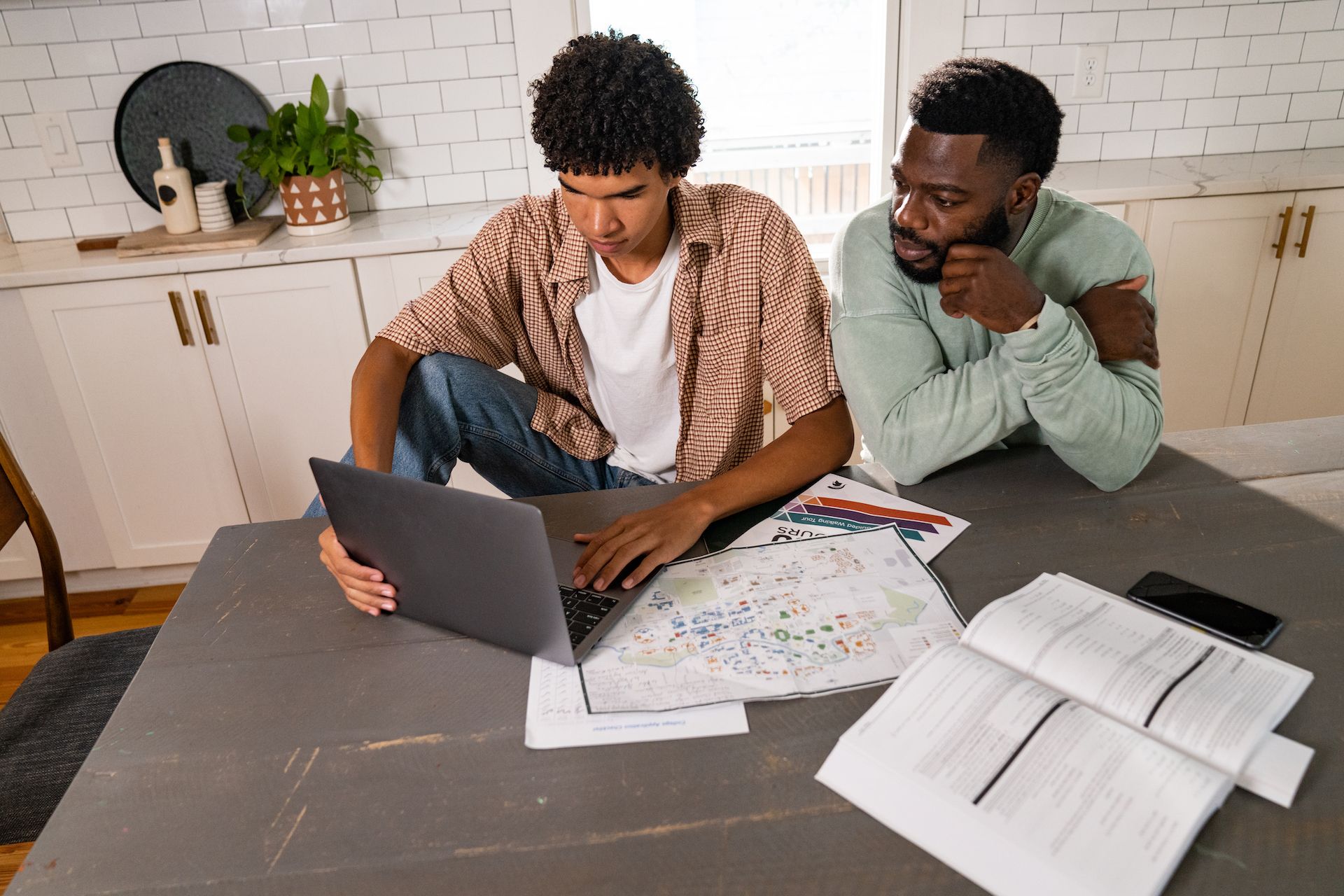 Two people sit together at a kitchen table with a new laptop, trying to figure out how to move their files to the new device.
