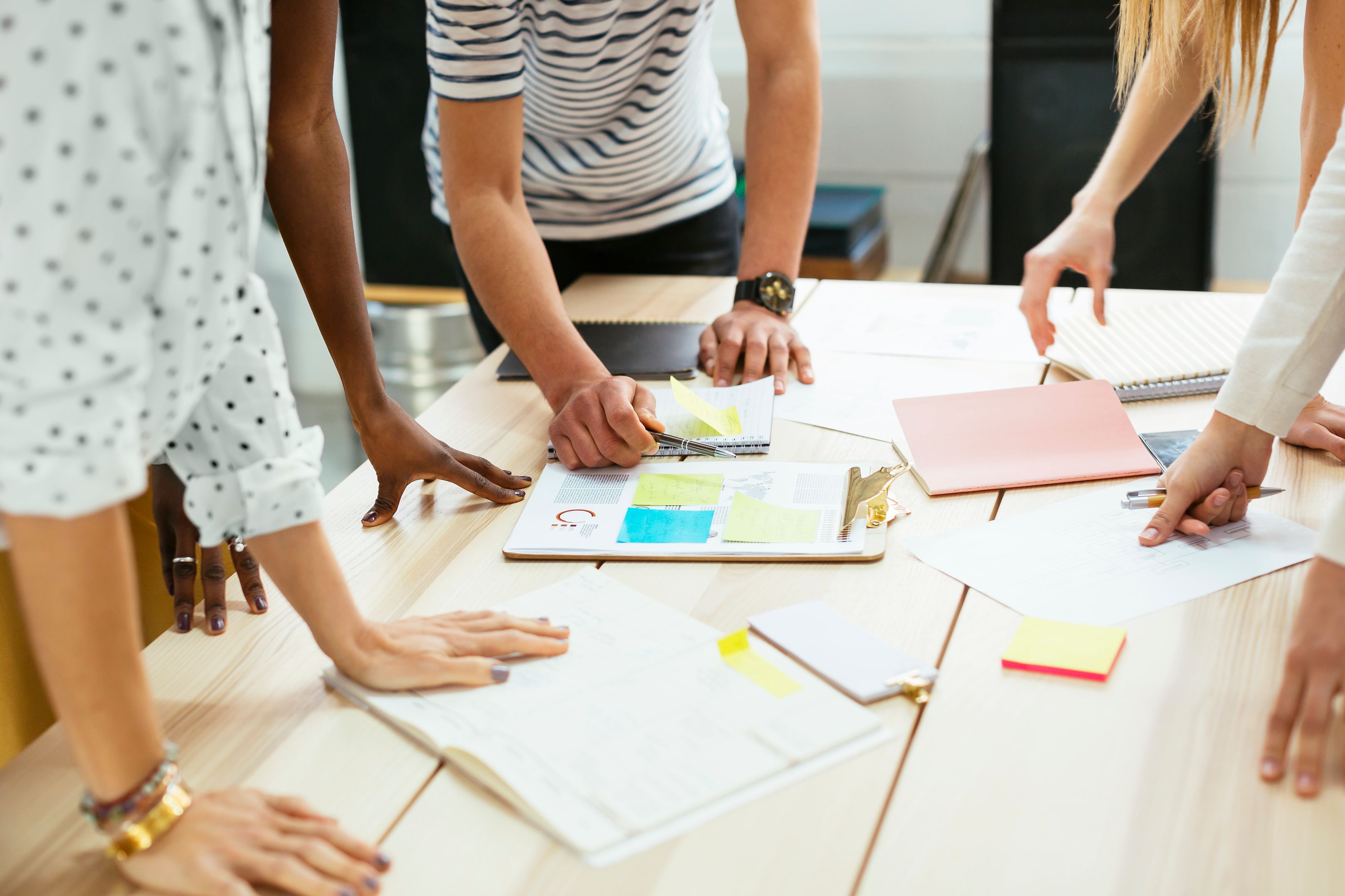 Close-up of colleagues looking at documents laid out on a table.