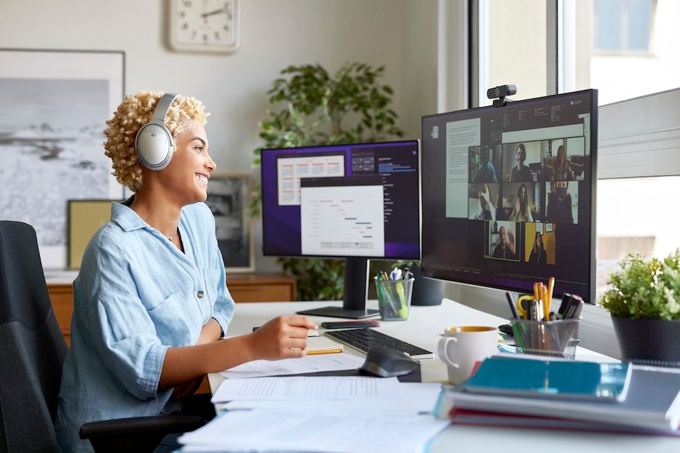 A solopreneur sits in front of their desk, looking at documents and smiling on a zoom call.