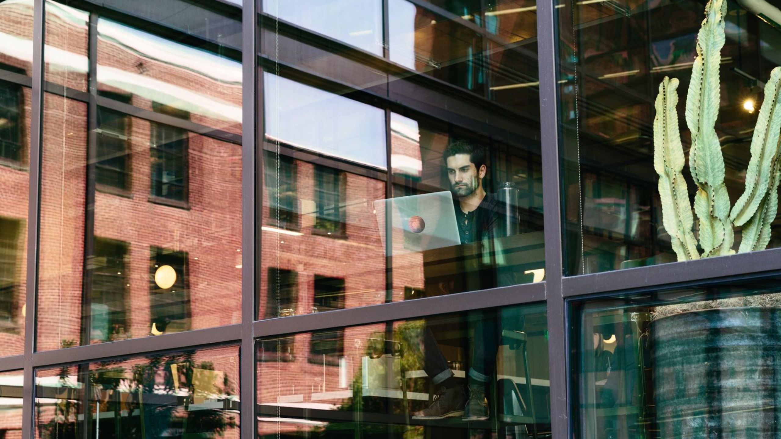 En mand med en åben bærbar computer i hænderne står foran et kontor