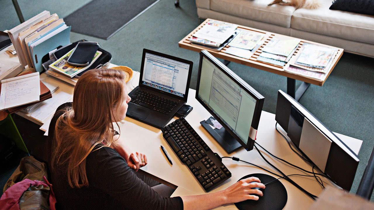 Жінка, що працює за столом, використовуючи кілька екранів