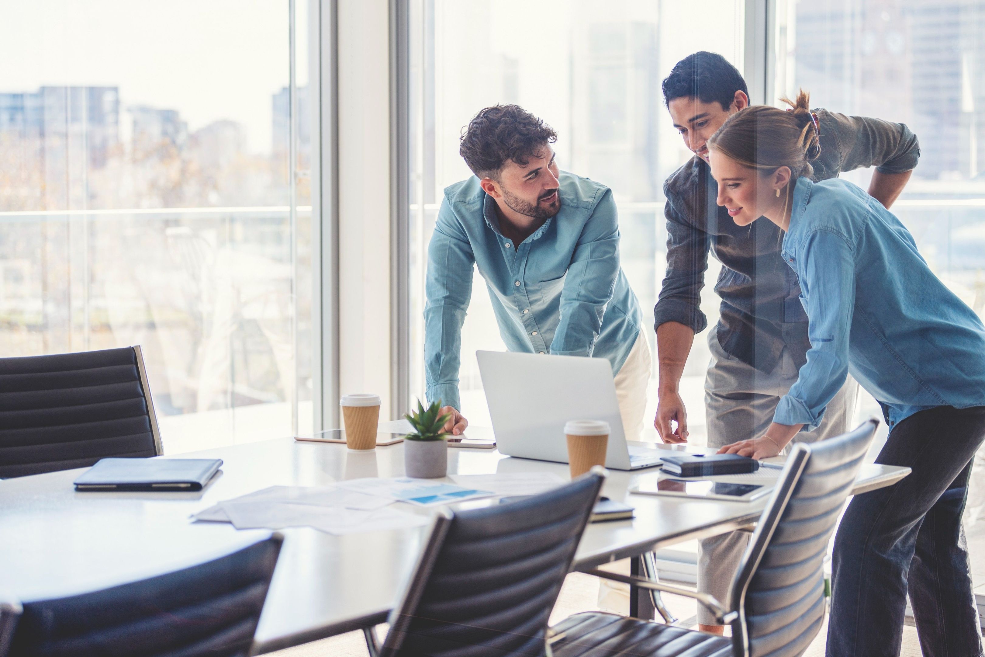 Trois personnes ensemble dans un bureau regardant un ordinateur