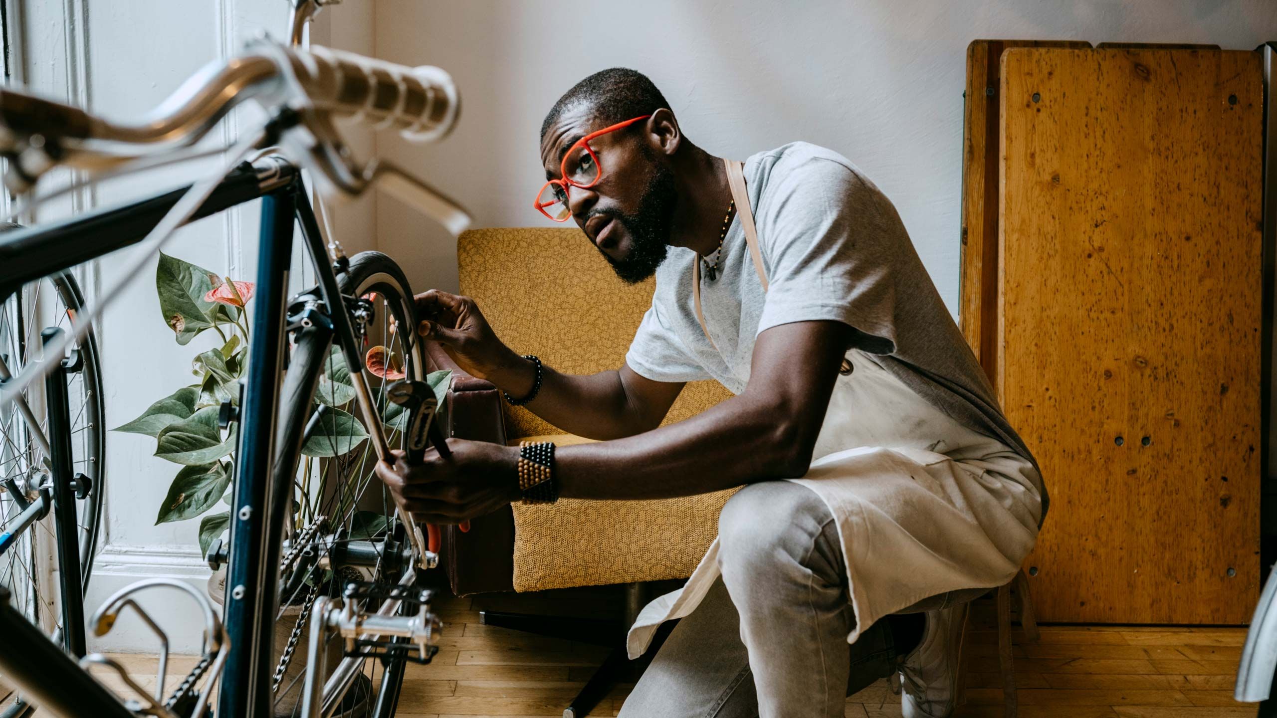 Un homme avec des lunettes rouges travaillant sur un vélo