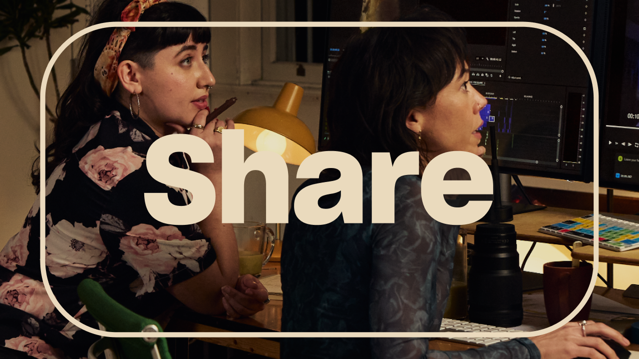 Two people collaborate at a desktop editing workstation in a warmly lit room, with large cream-colored text reading “Share” over the image.