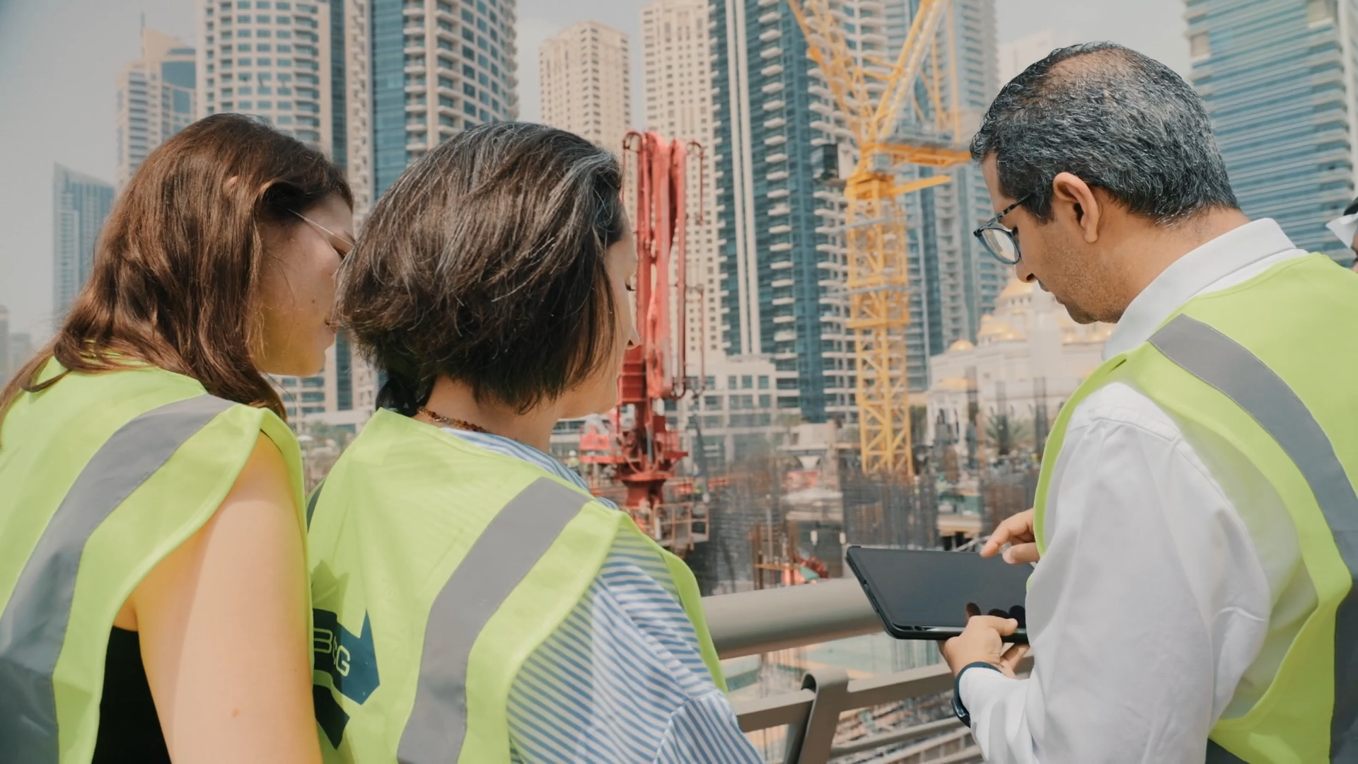 Tre personer, der kigger på en tablet på en byggeplads