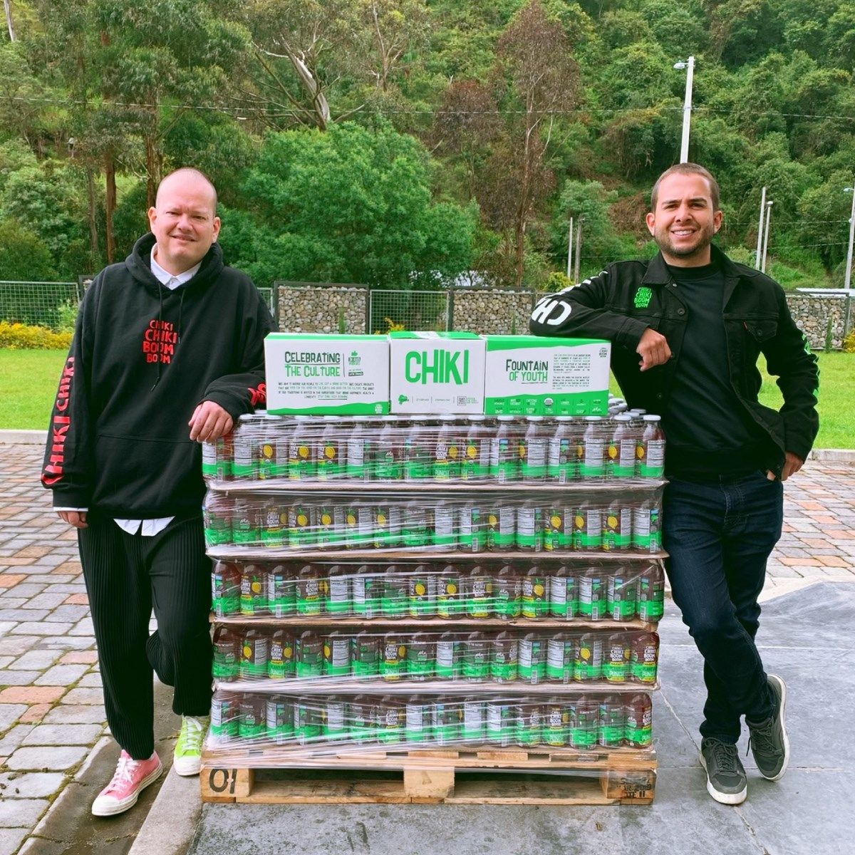 Two men standing on either side of a pallet of drinks