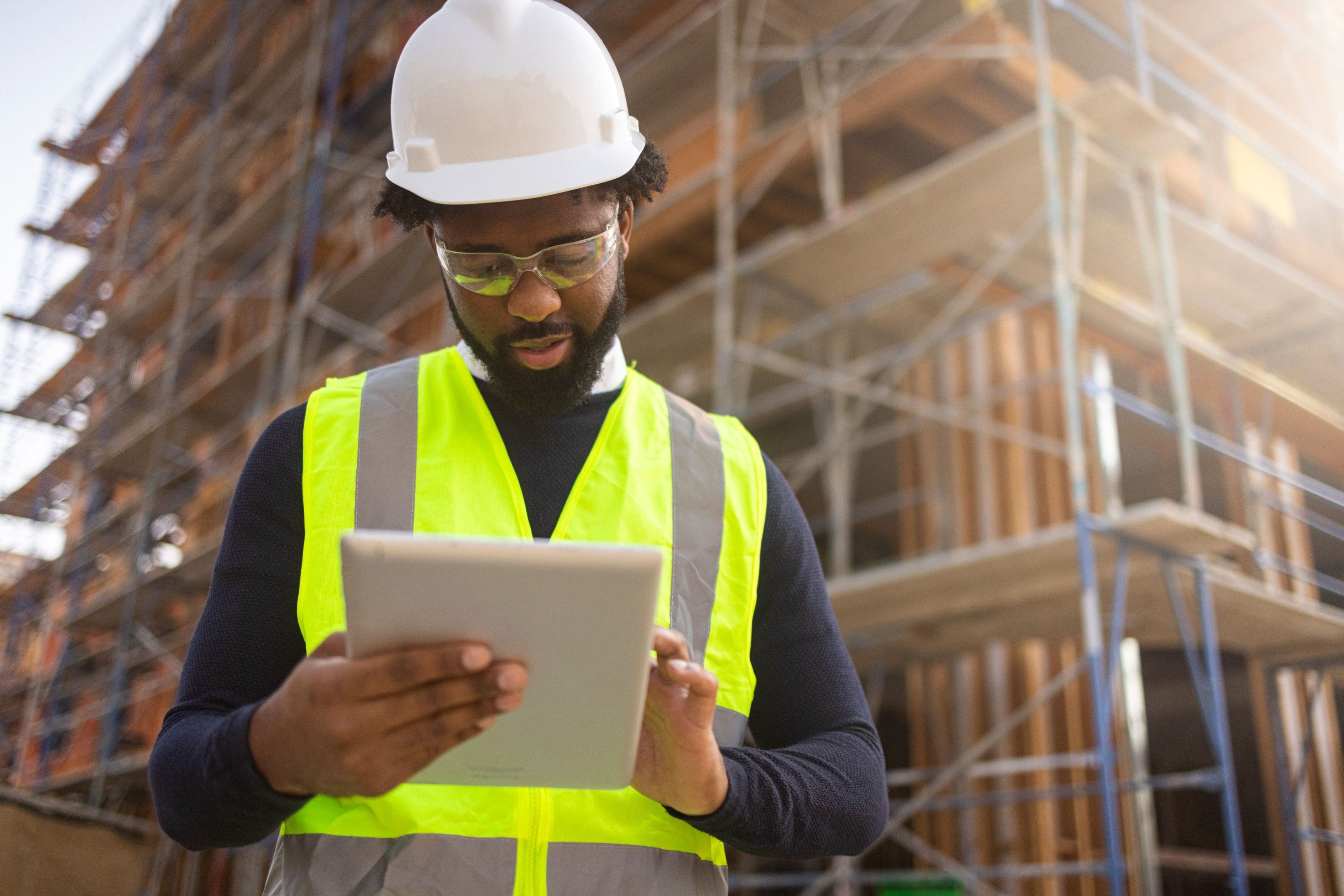 Man outside on tablet in front of building under construction