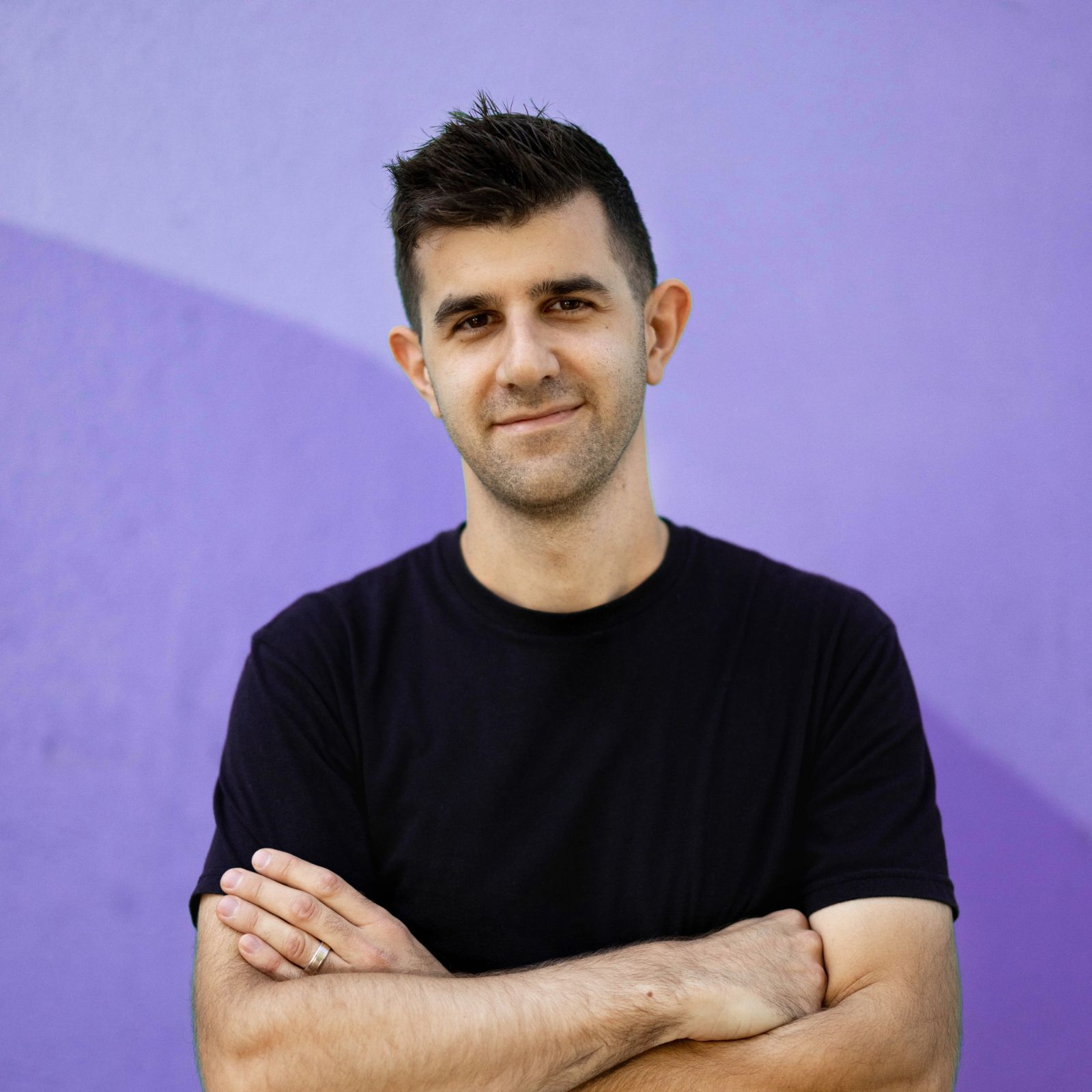 Chris Grubisa standing in front of a purple wall in a black t-shirt
