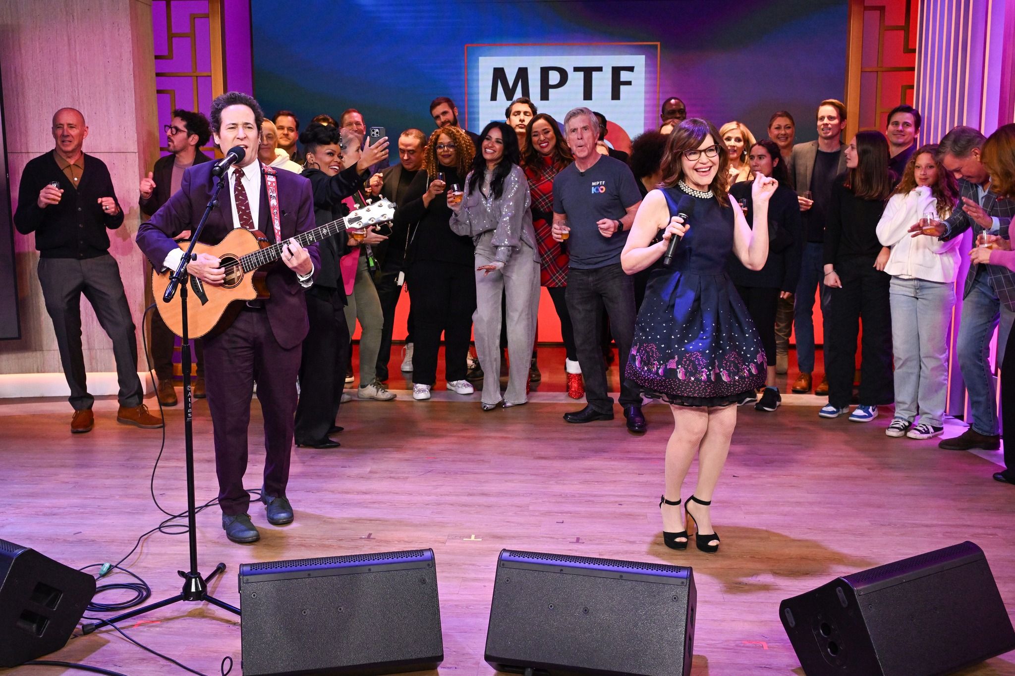 Male and female performing with crowd behind them