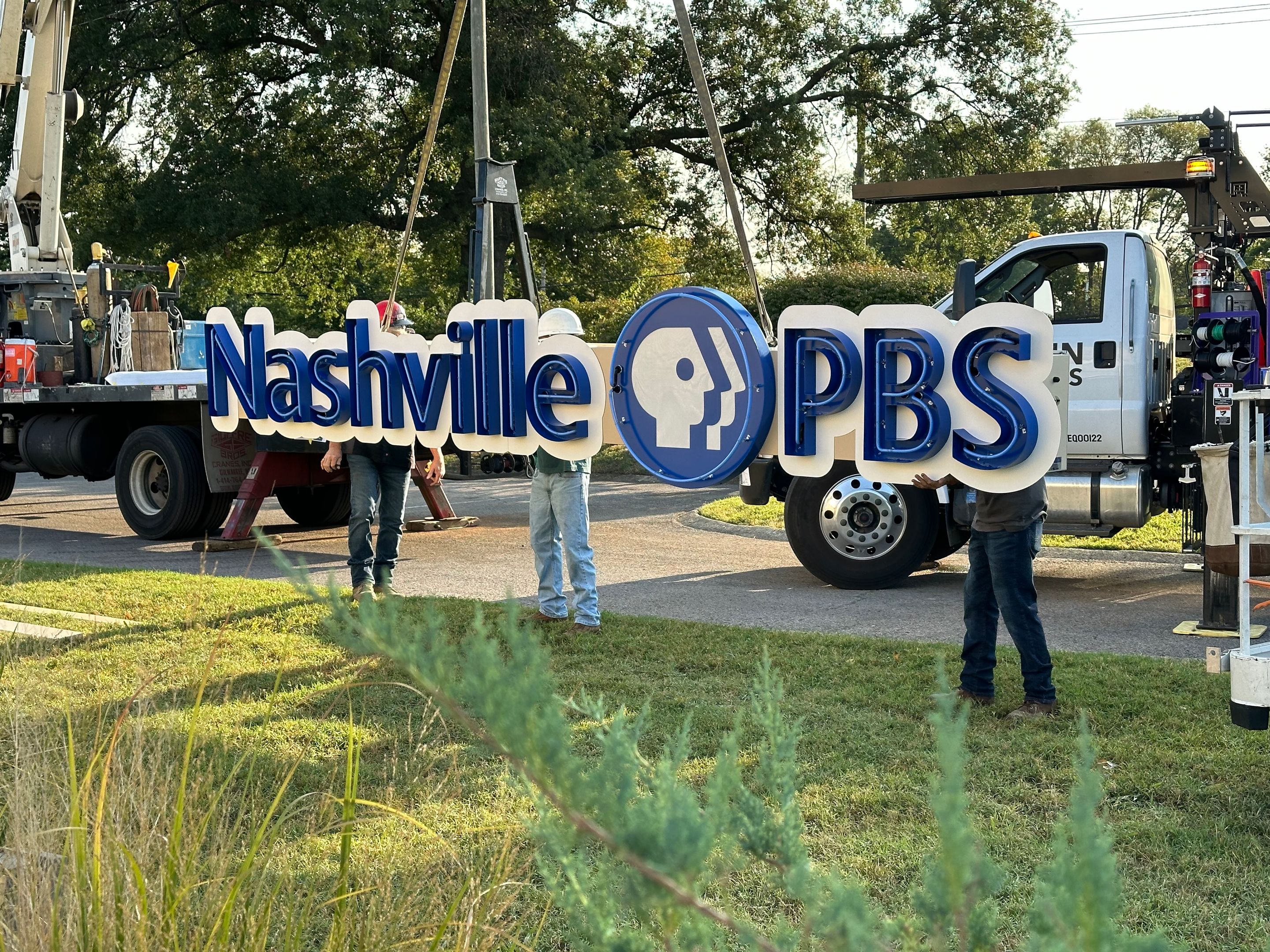 Nashville PBS sign being lifted by ropes attached to a crane.