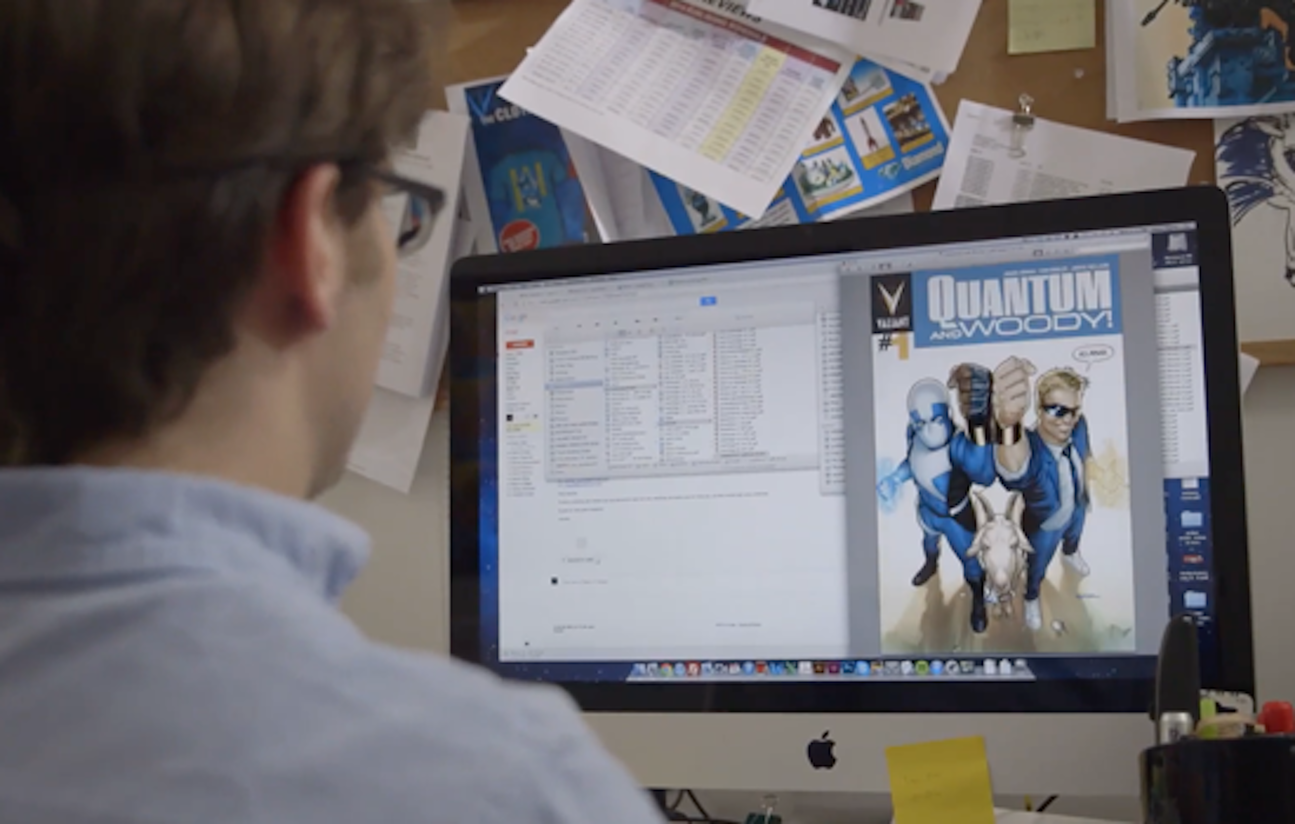 Person sitting at a computer editing a comic book cover.