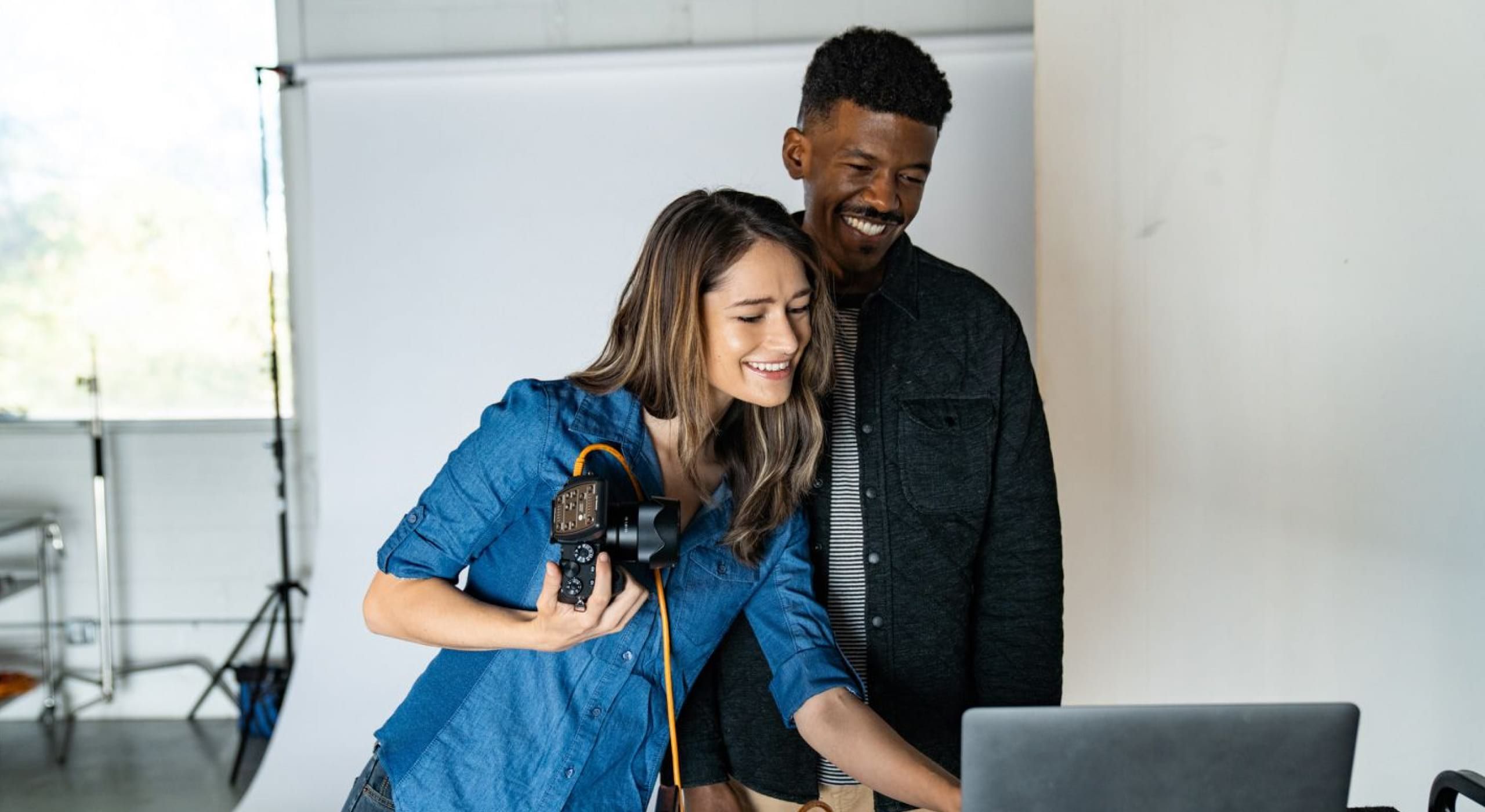 Een man en een vrouw die op een laptop naar afbeeldingen kijken van een digitale camera.