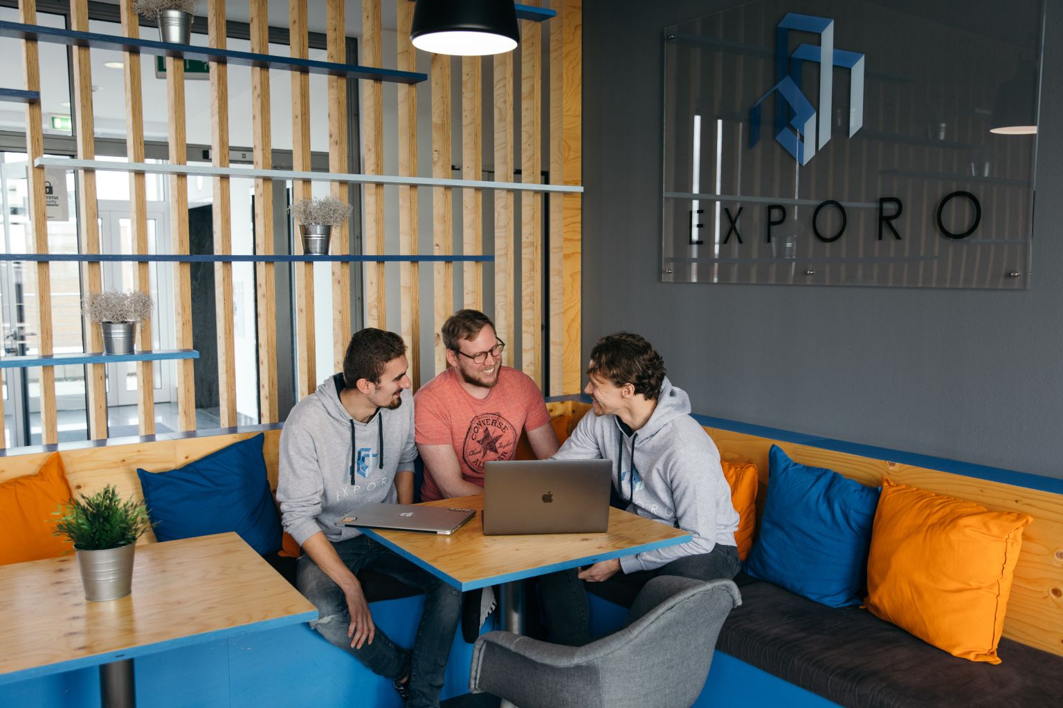 Three men sit around a laptop at the Exporo office.