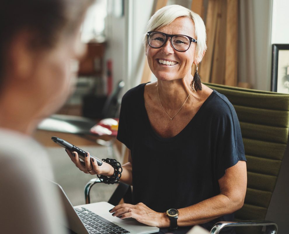 Smiling woman works on mobile phone and computer