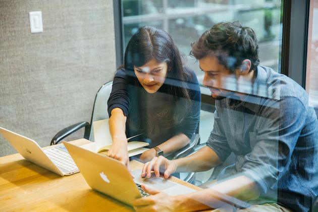 Een vrouw wijst naar een schermopname op de laptop van een man