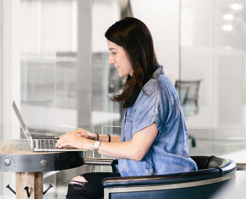 Frau arbeitet mit einem Laptop an einem Tisch