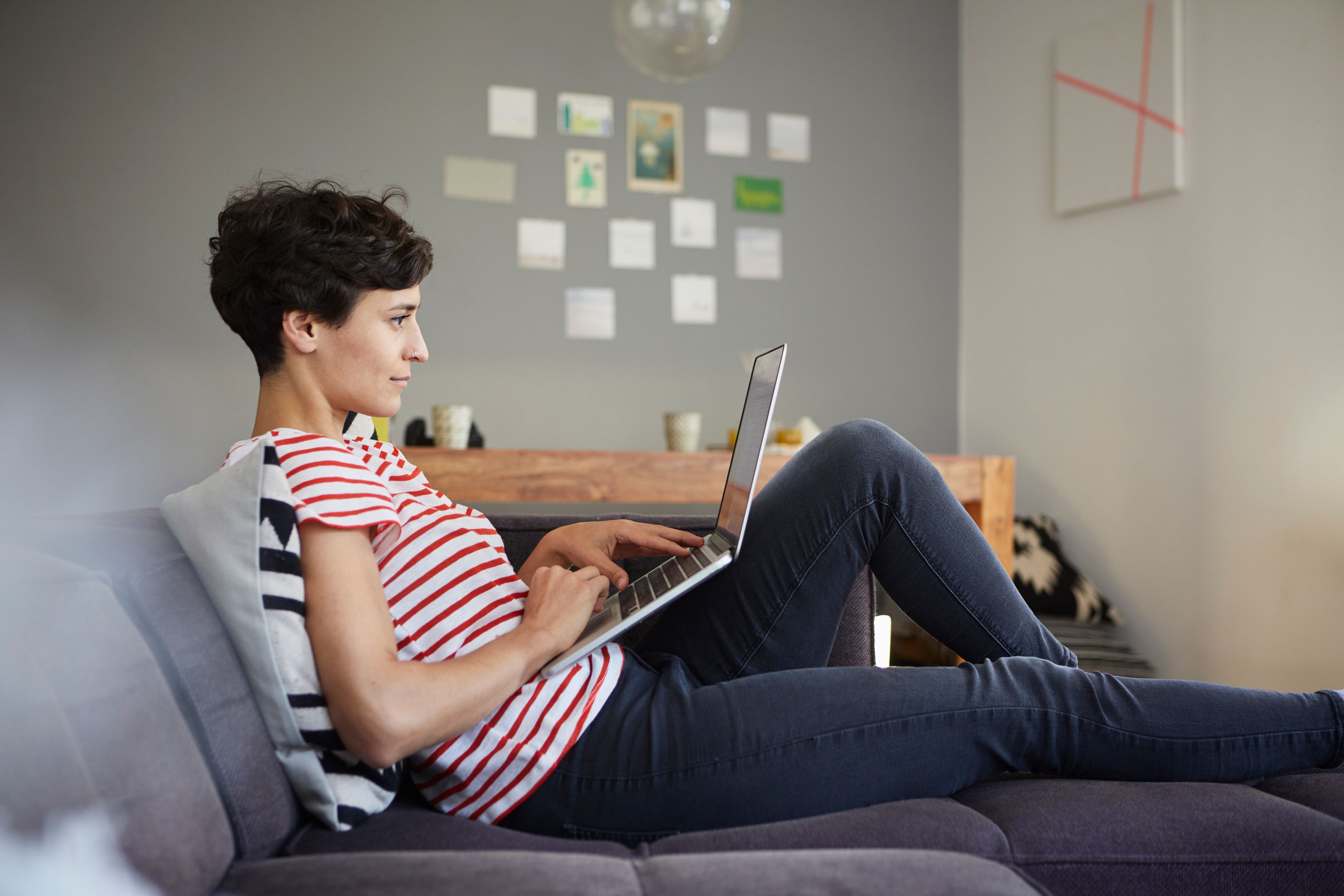 A person working on a laptop reclined on their couch.