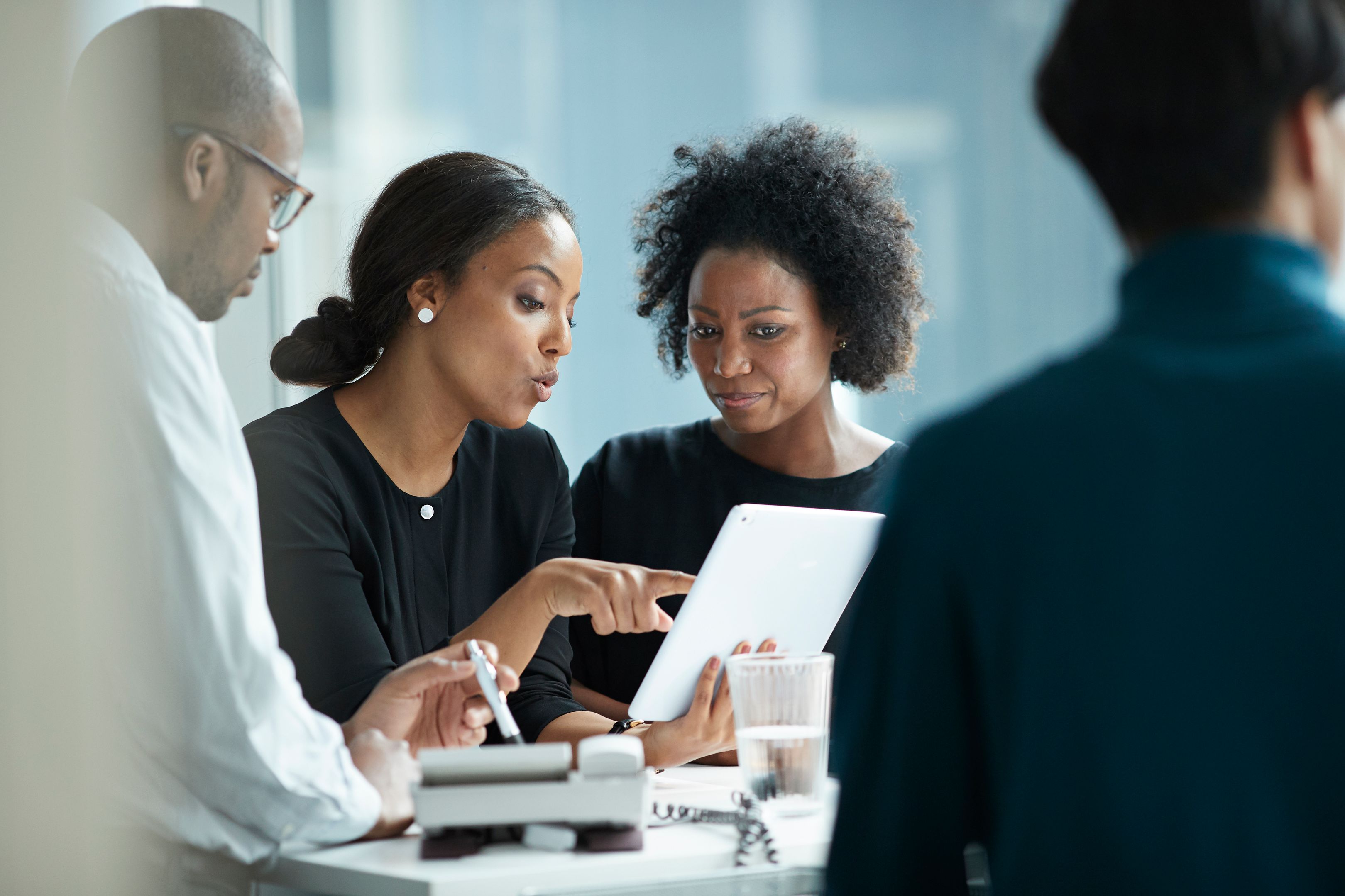 Three people in an office sat around a tablet.