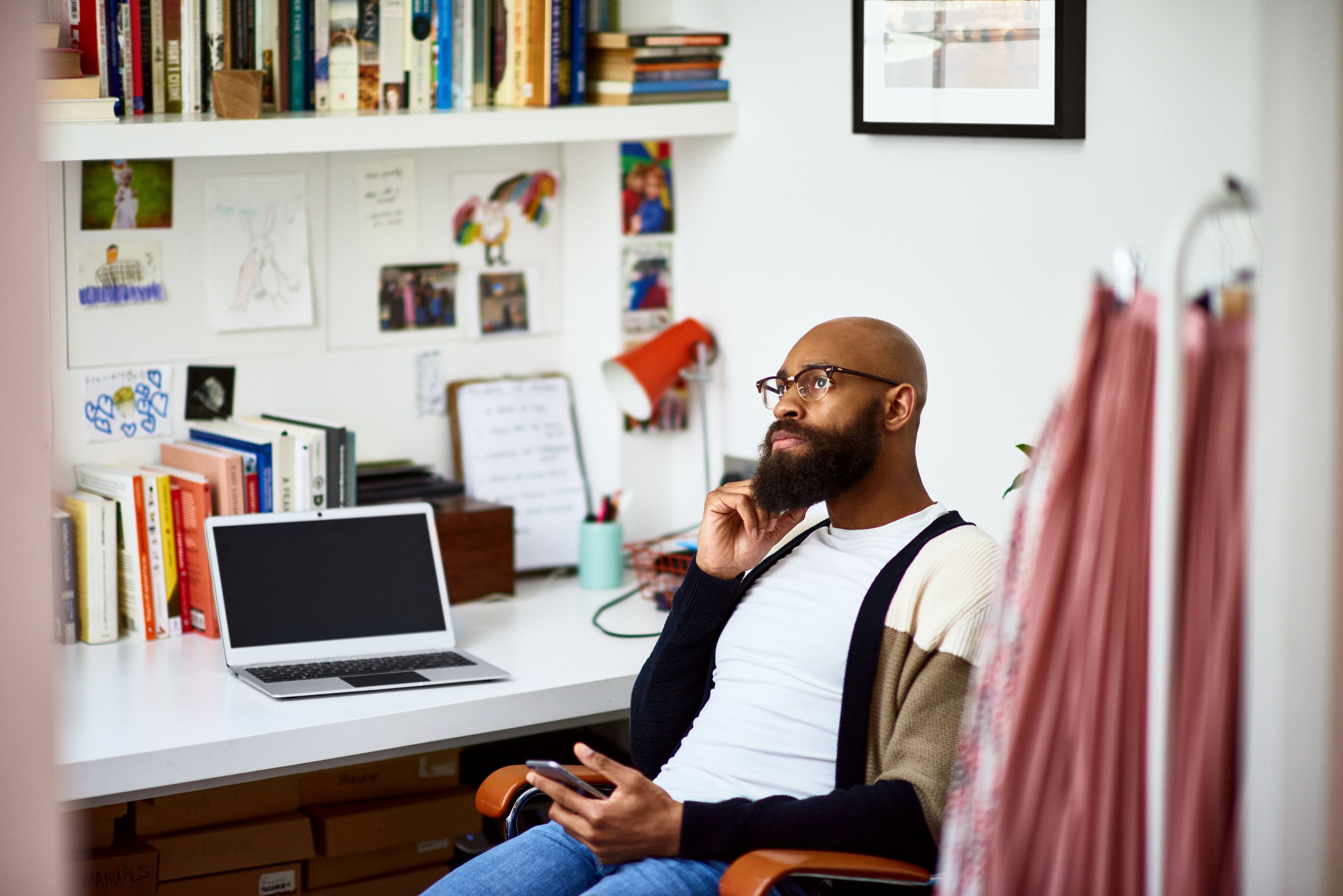 A person in their home office, looking off into the distance.