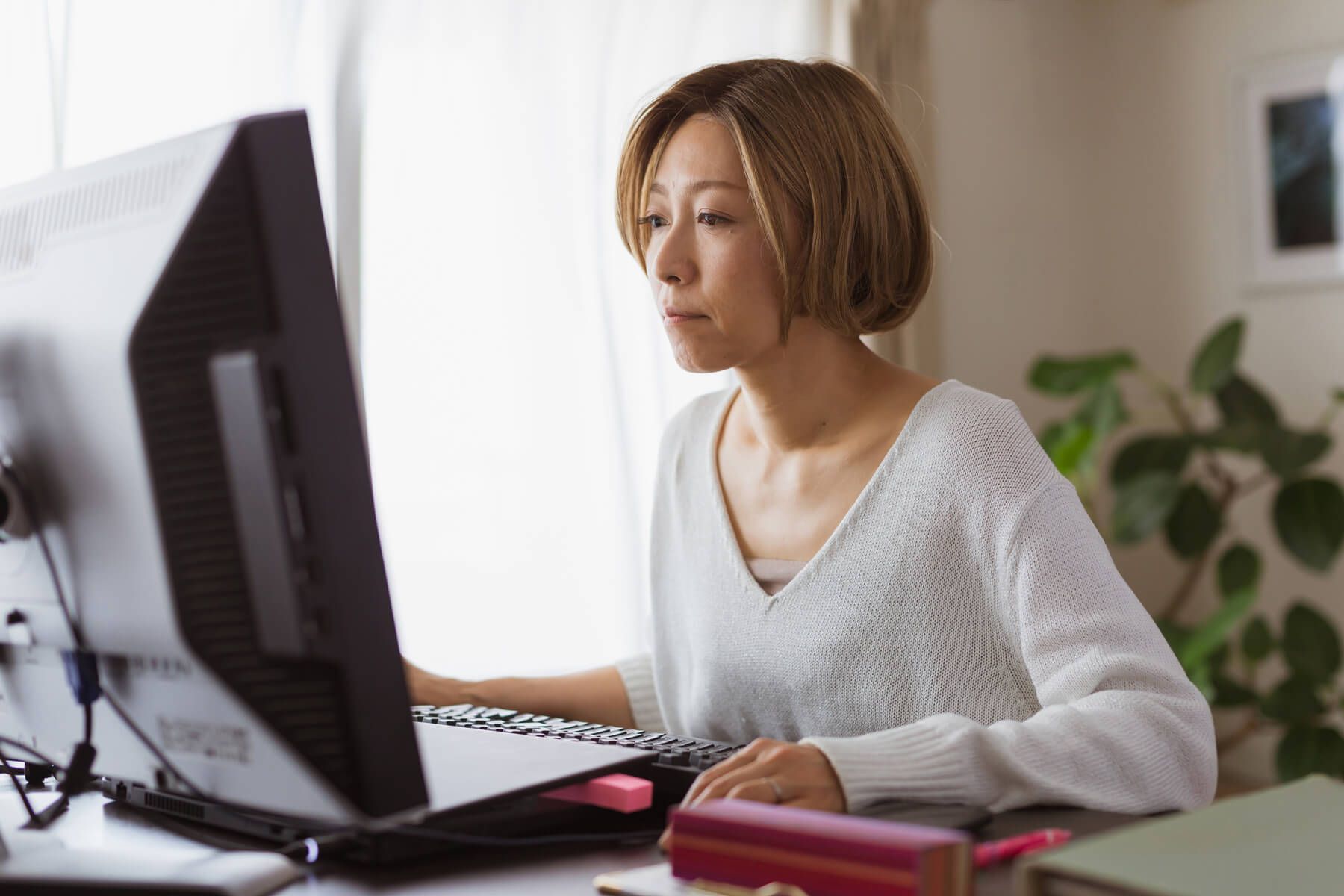 A person concentrates on their desktop while working at home.