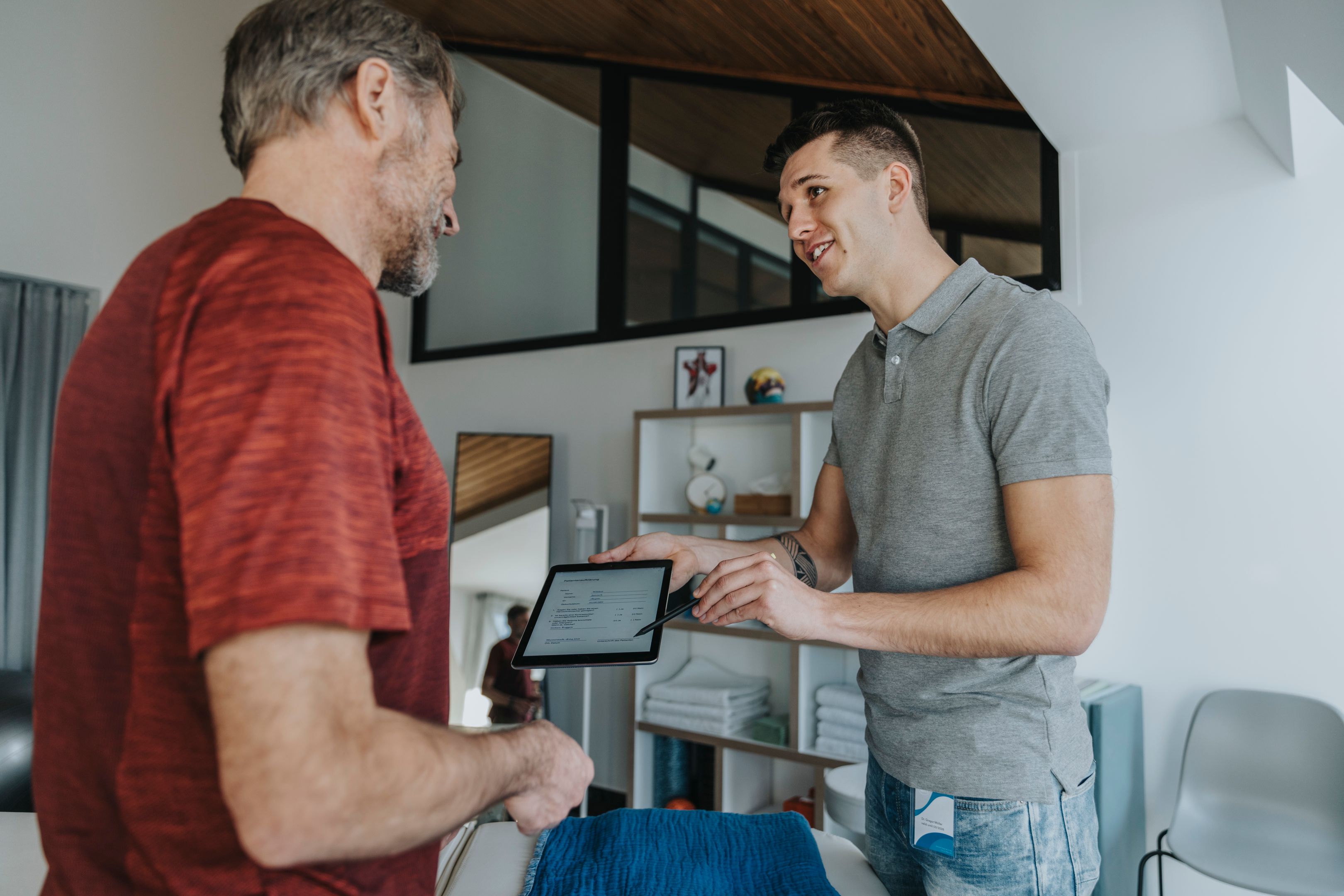 A seller talking to a buyer in a room holding a tablet.