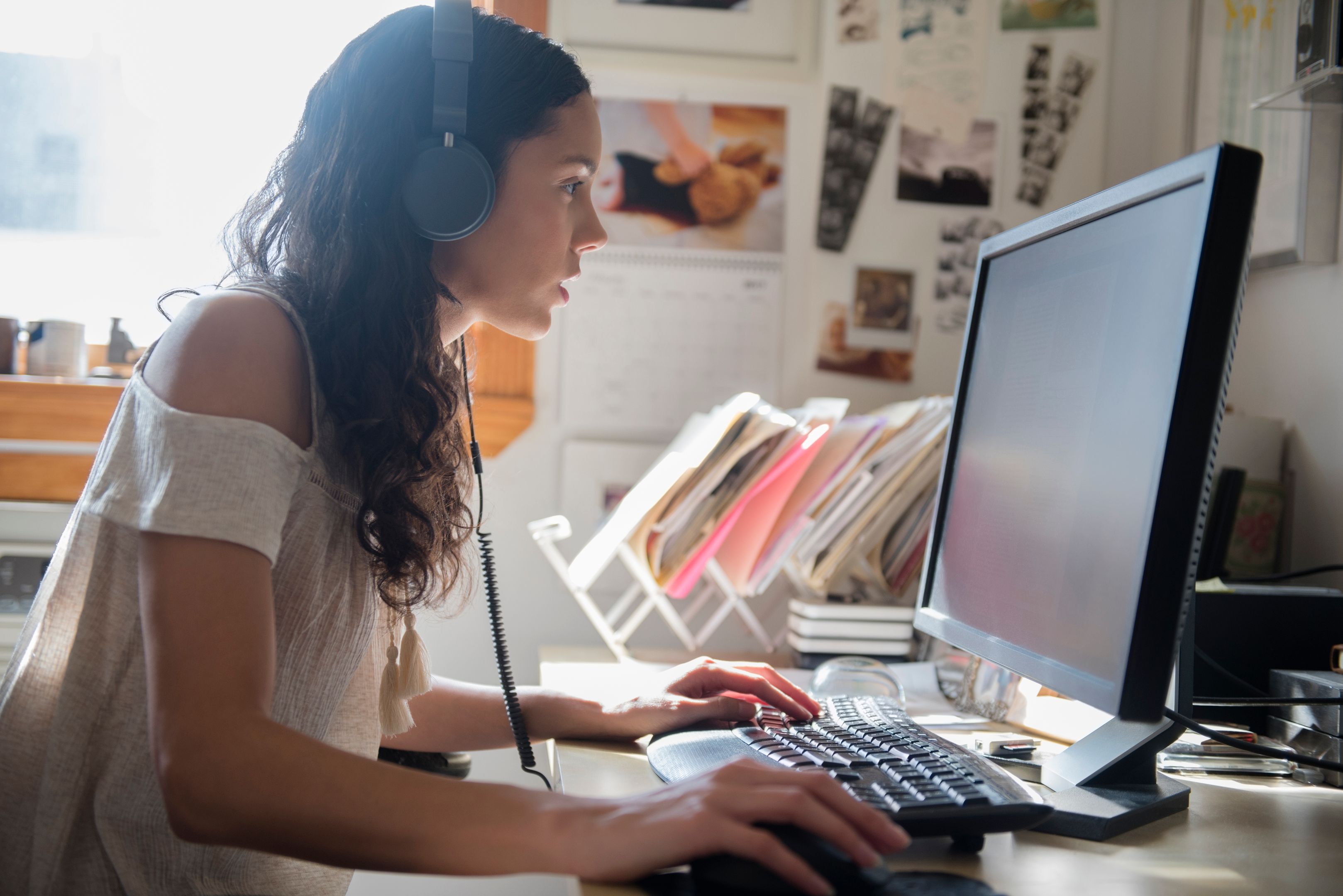 A person working at their desktop wearing headphones.