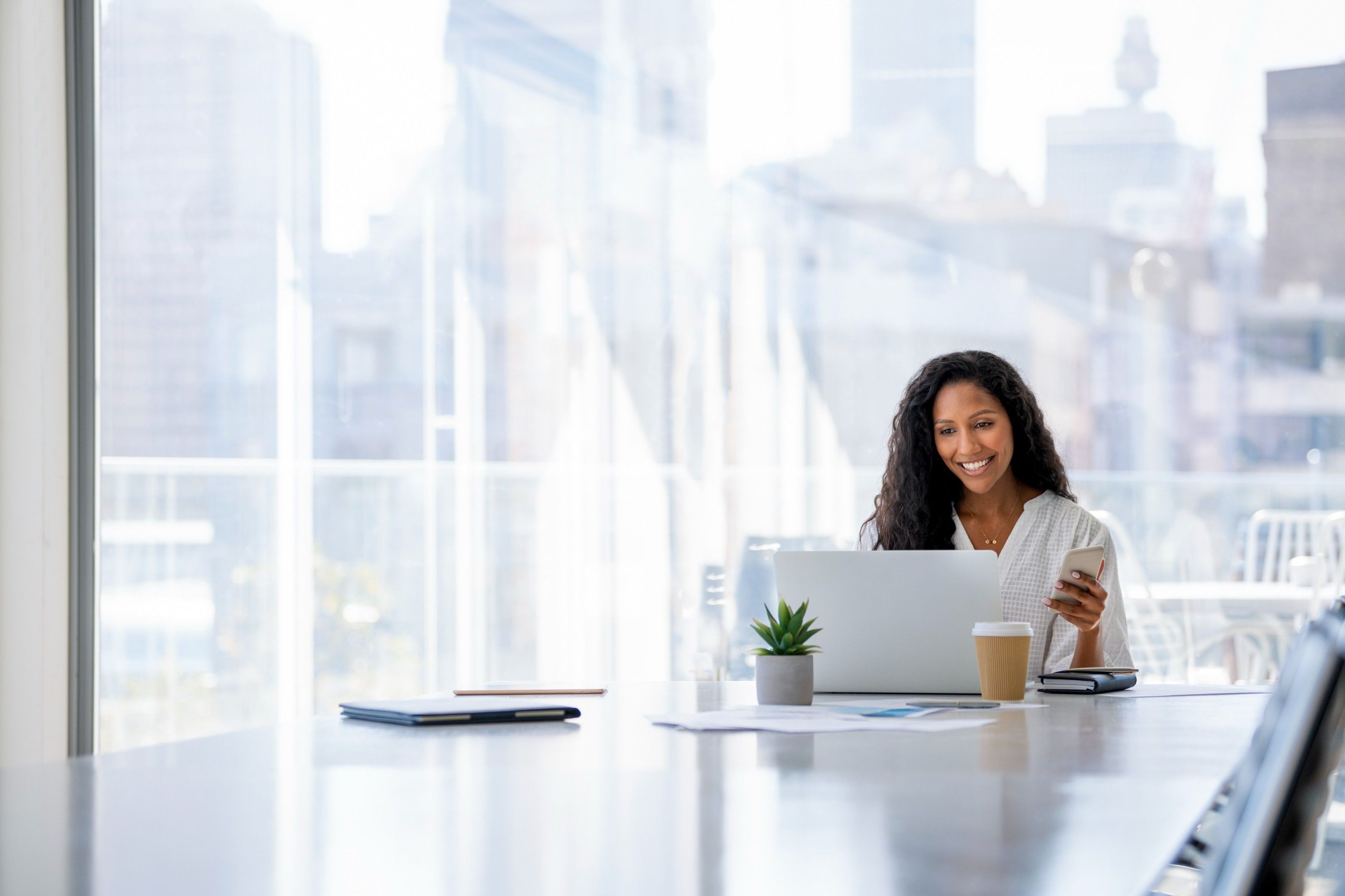 A person sat at the end of a table in a boardroom on their laptop.