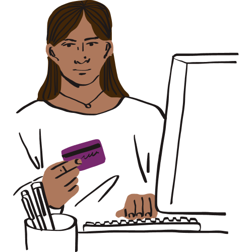 A person holds their bank card while working on a desktop.