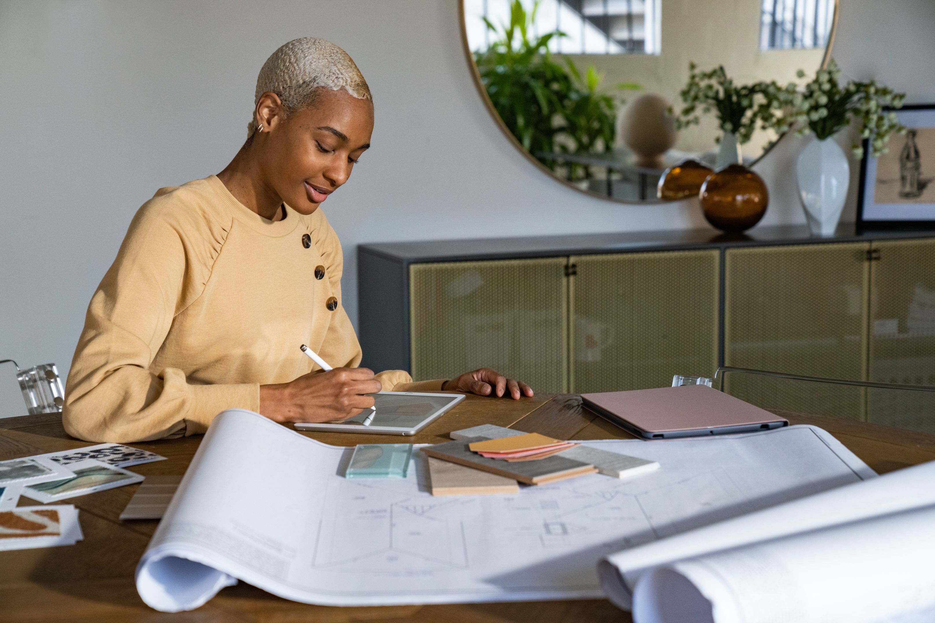 A person working at home from a tablet with blueprints.
