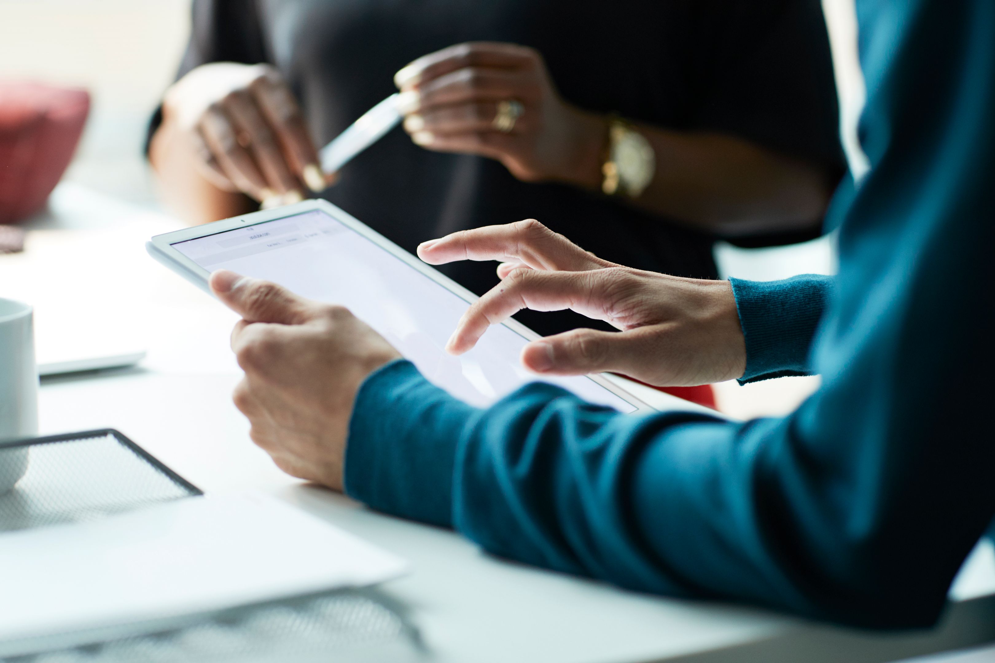 A person consults the meeting notes on their tablet during a discussion.