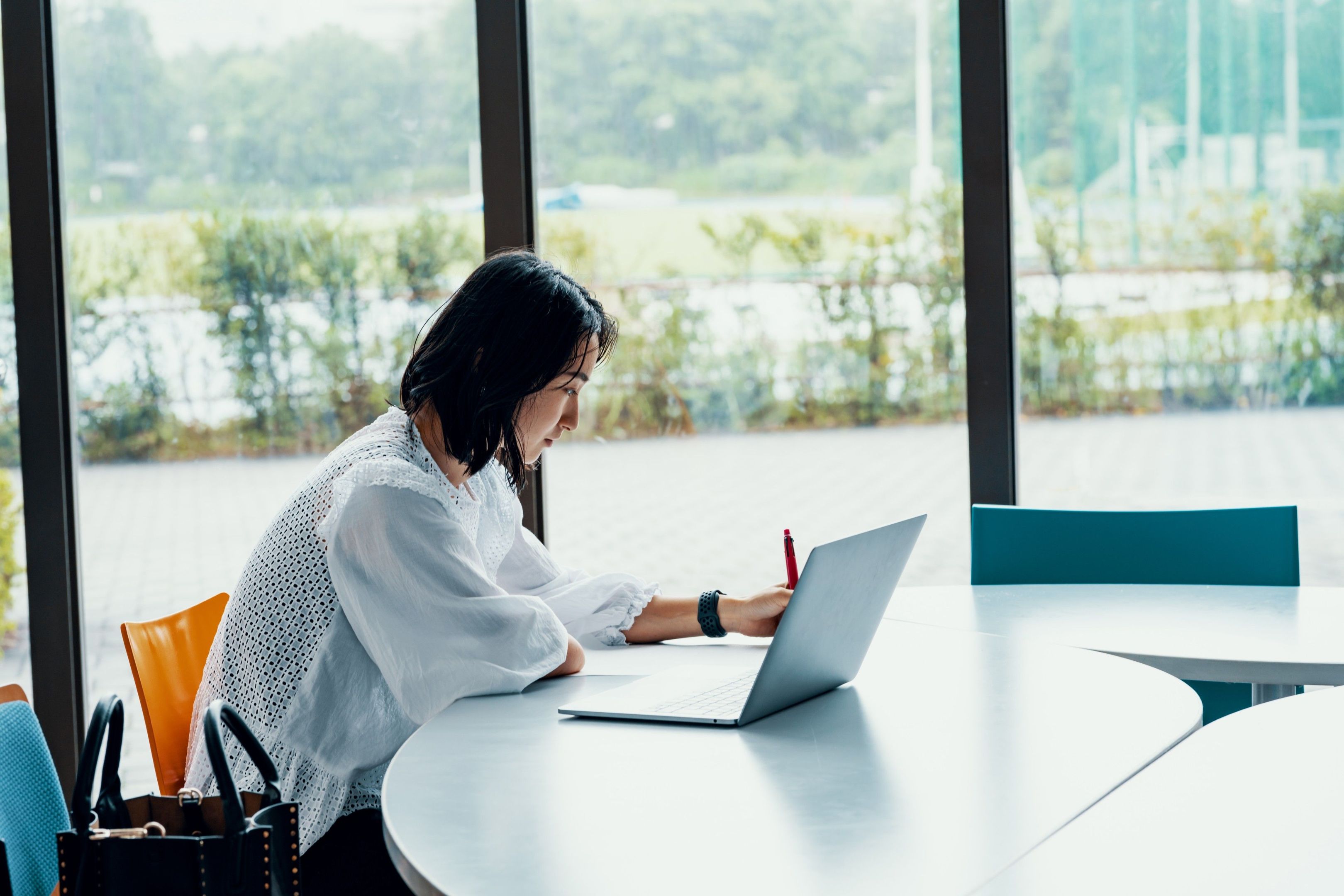 A person works on a laptop in a glass panelled room.