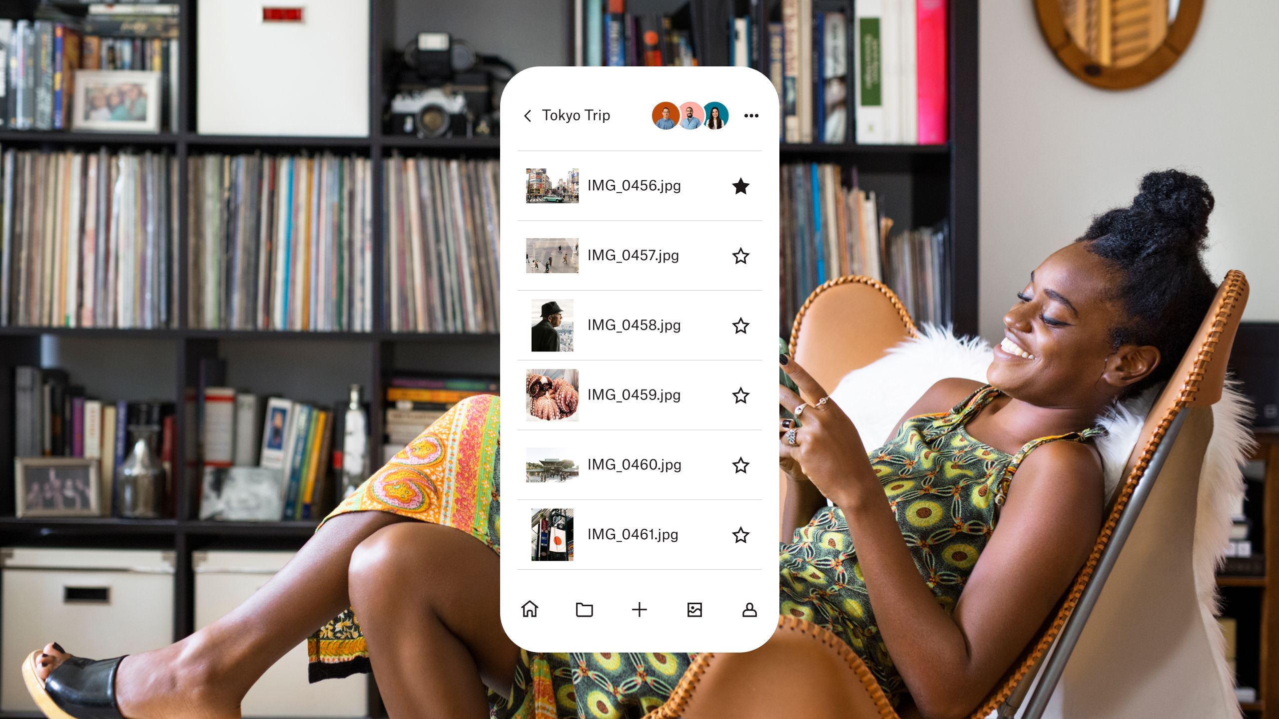 A woman sitting in a chair looking at photos she has saved in Dropbox