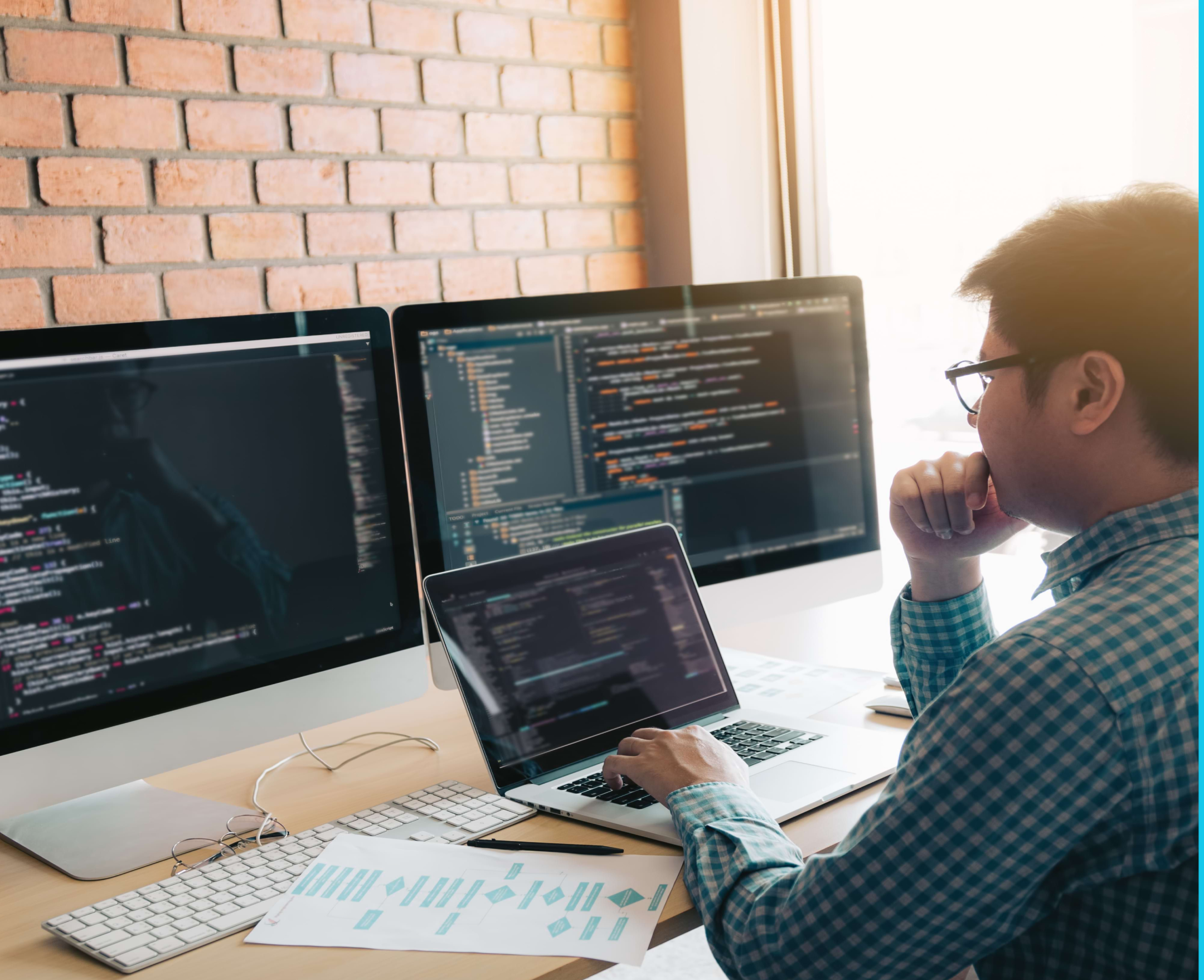 An IT professional coding on 3 different screens