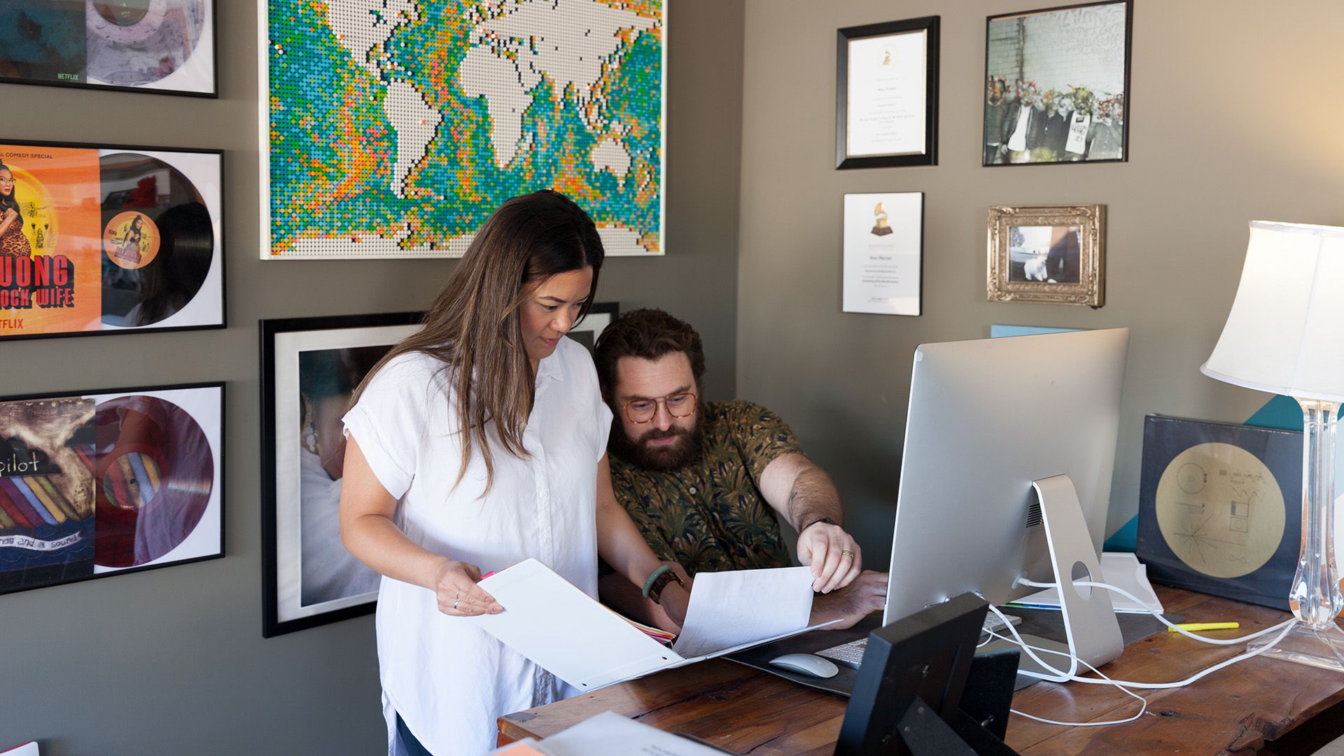 Two people look at some documents together while working at a desk.